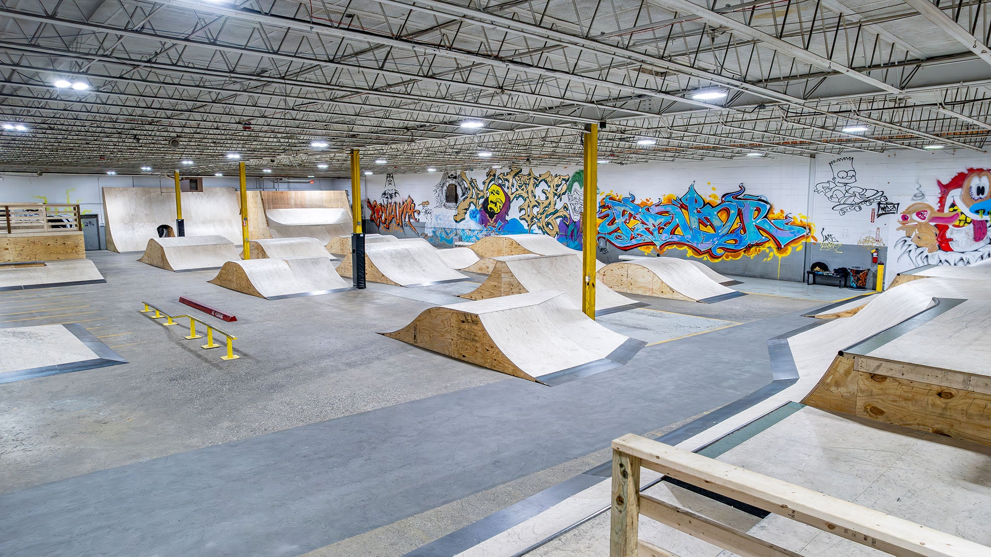Indoor skate park with various ramps and graffiti on the walls.