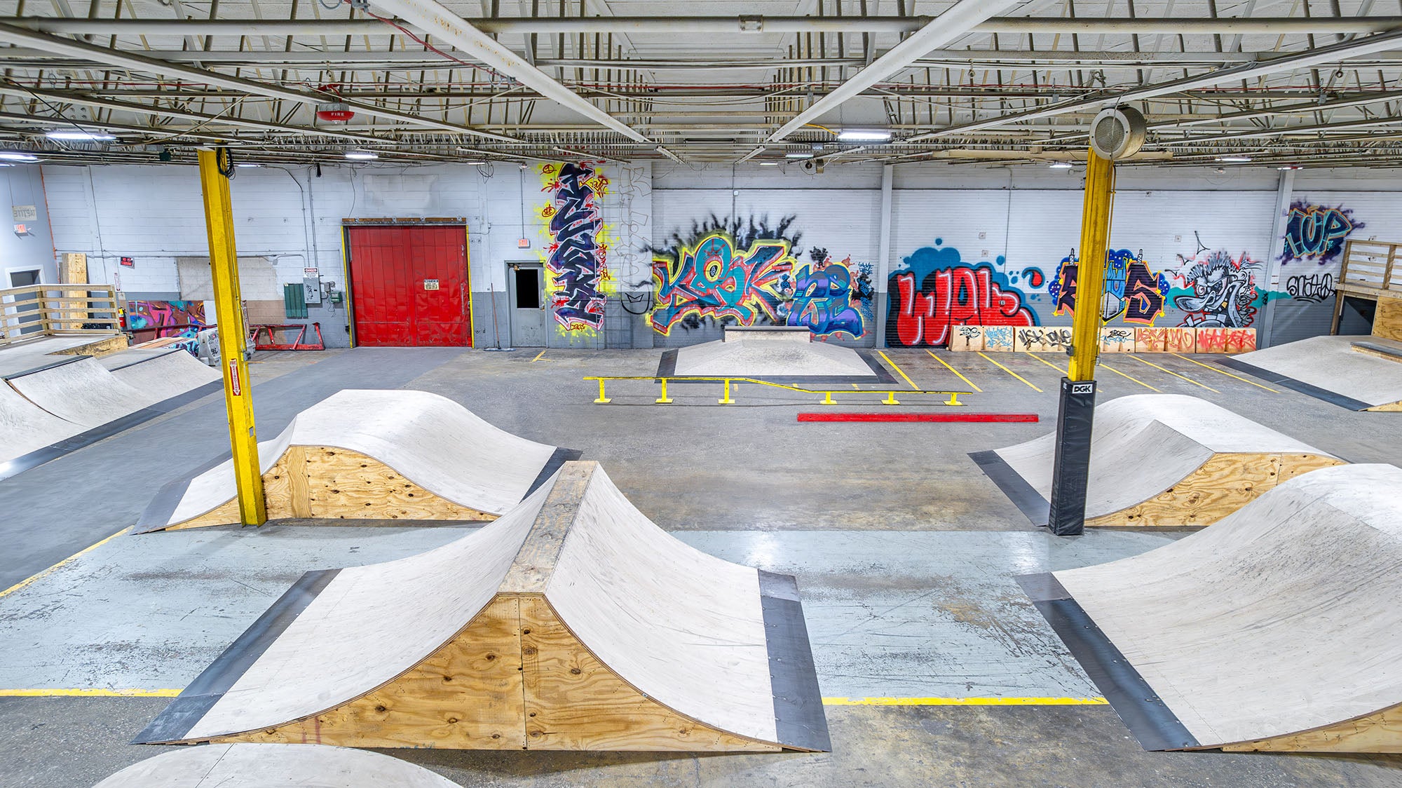 Indoor skate park with ramps and graffiti art on the walls.