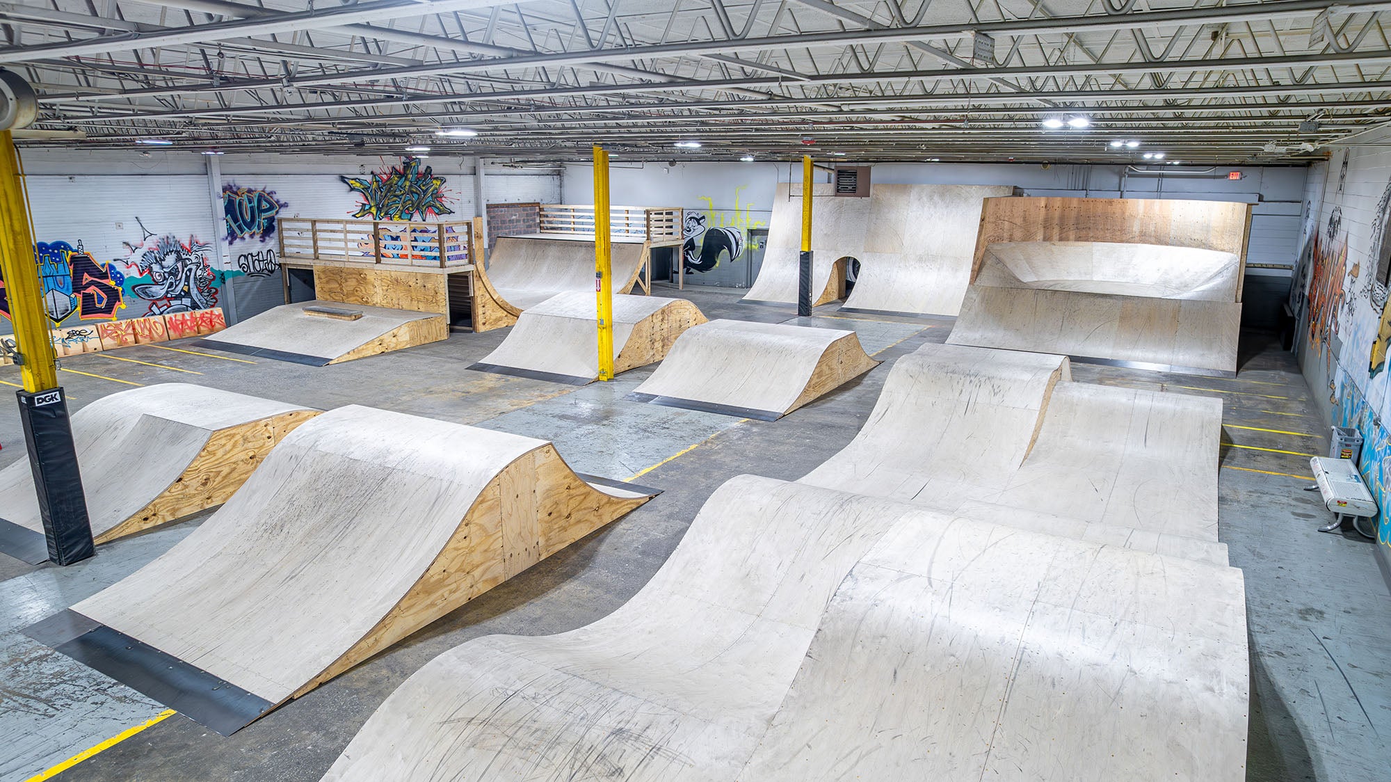 Indoor skate park with various ramps and graffiti on the walls.
