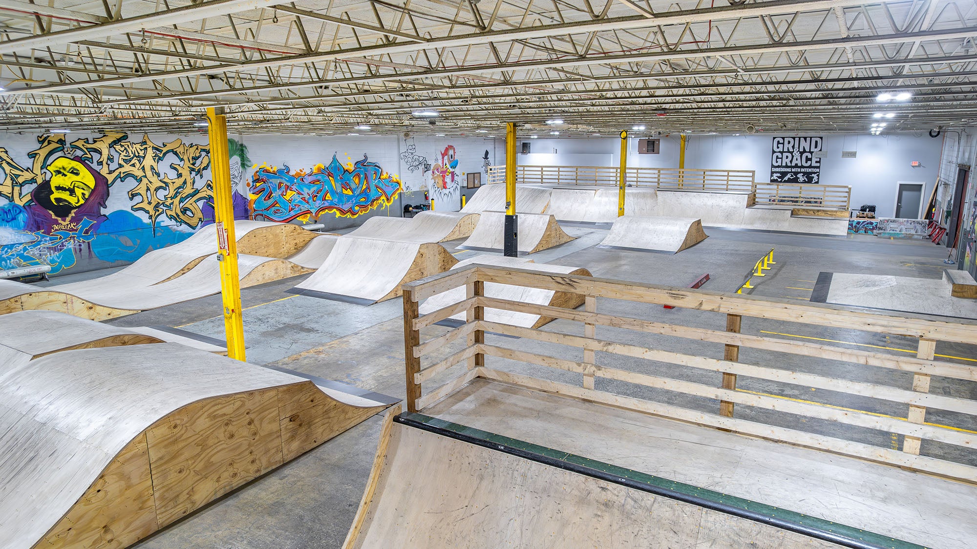 Indoor skate park with various ramps and graffiti art on the walls.