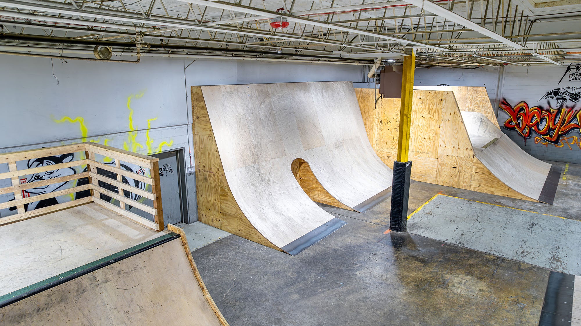 Indoor skate park with ramps and graffiti on the walls.