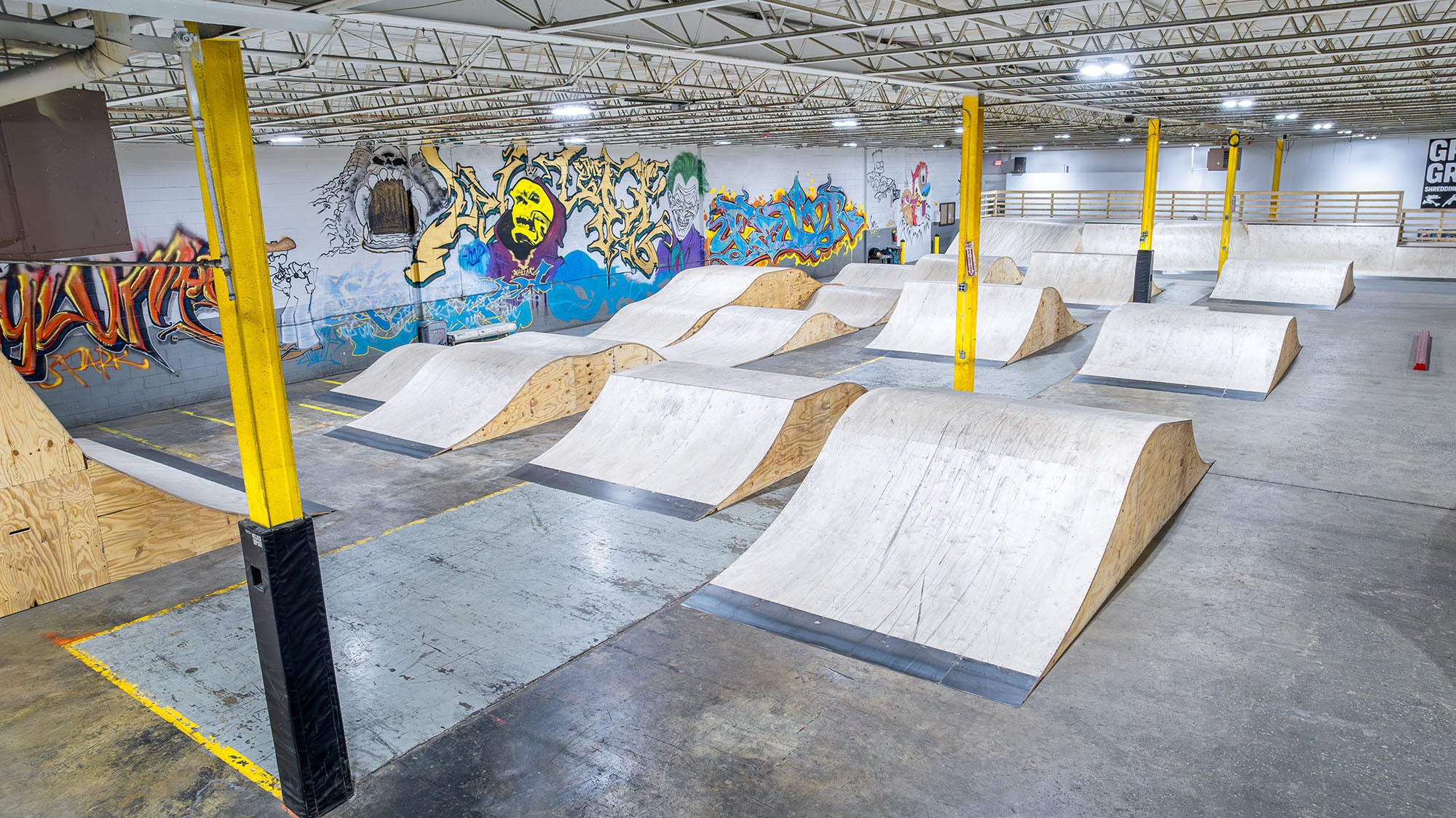 Indoor skate park with various ramps and graffiti art on the walls.