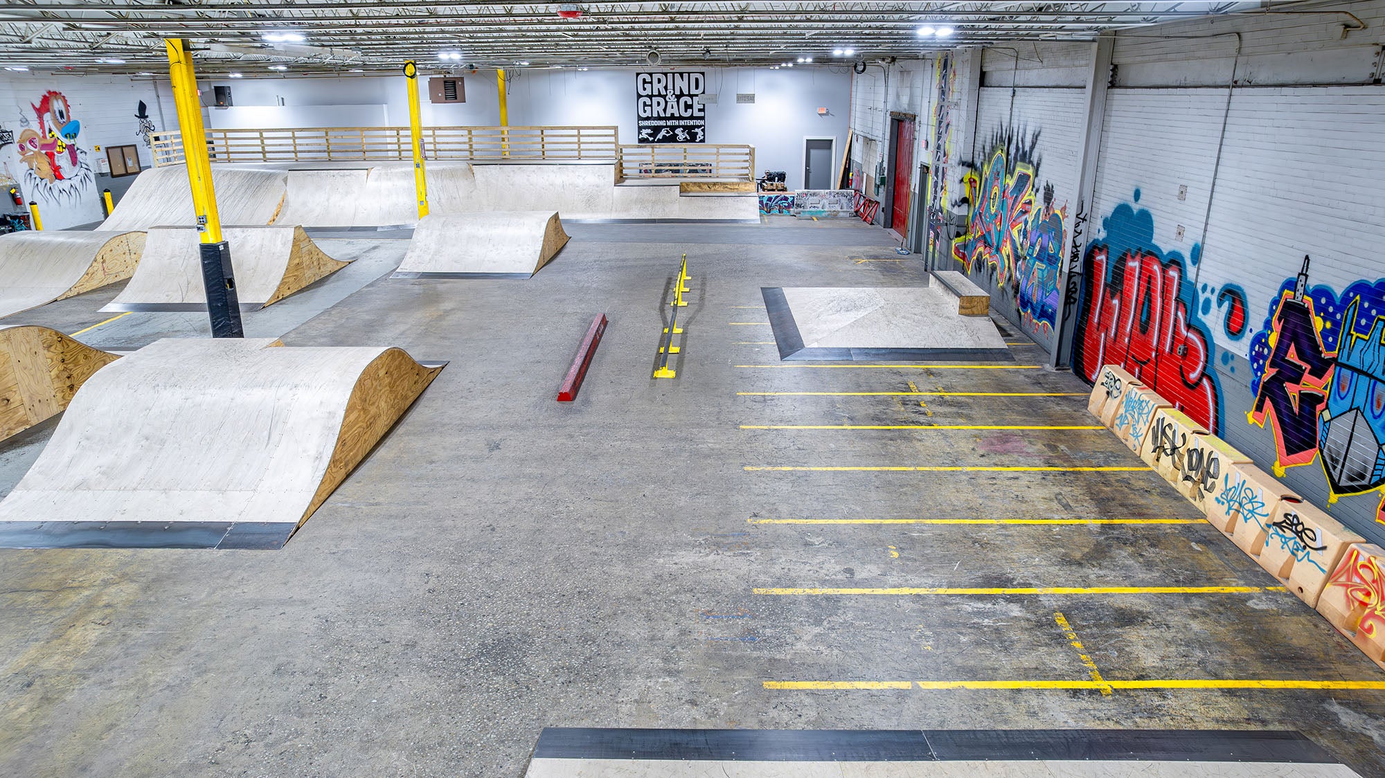 Indoor skate park with ramps and graffiti on the walls.