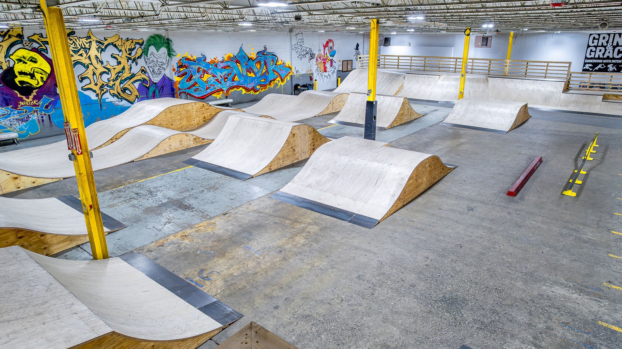 Indoor skate park with various ramps and graffiti art on the walls.