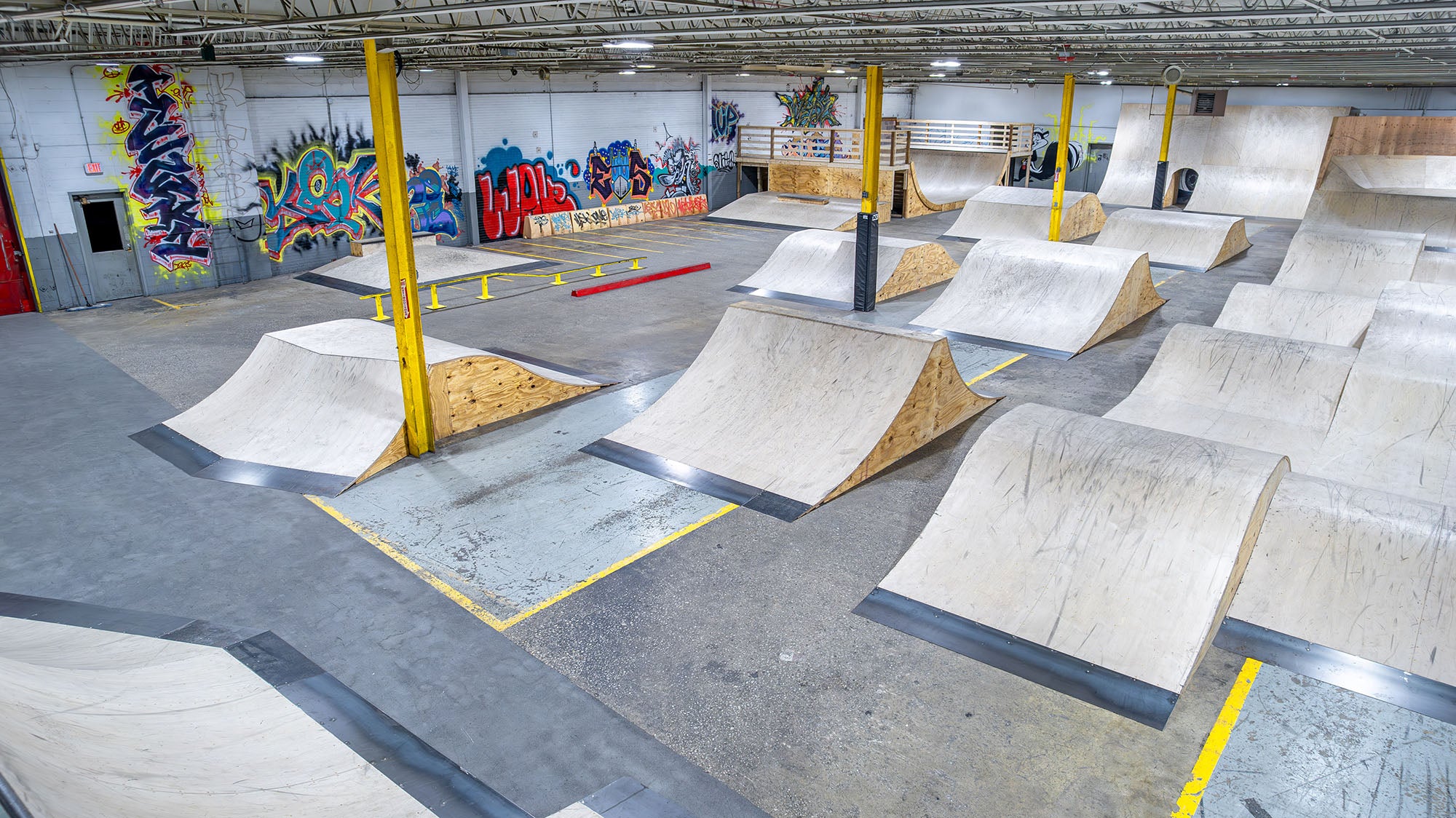 Indoor skate park with various ramps and graffiti art on the walls.