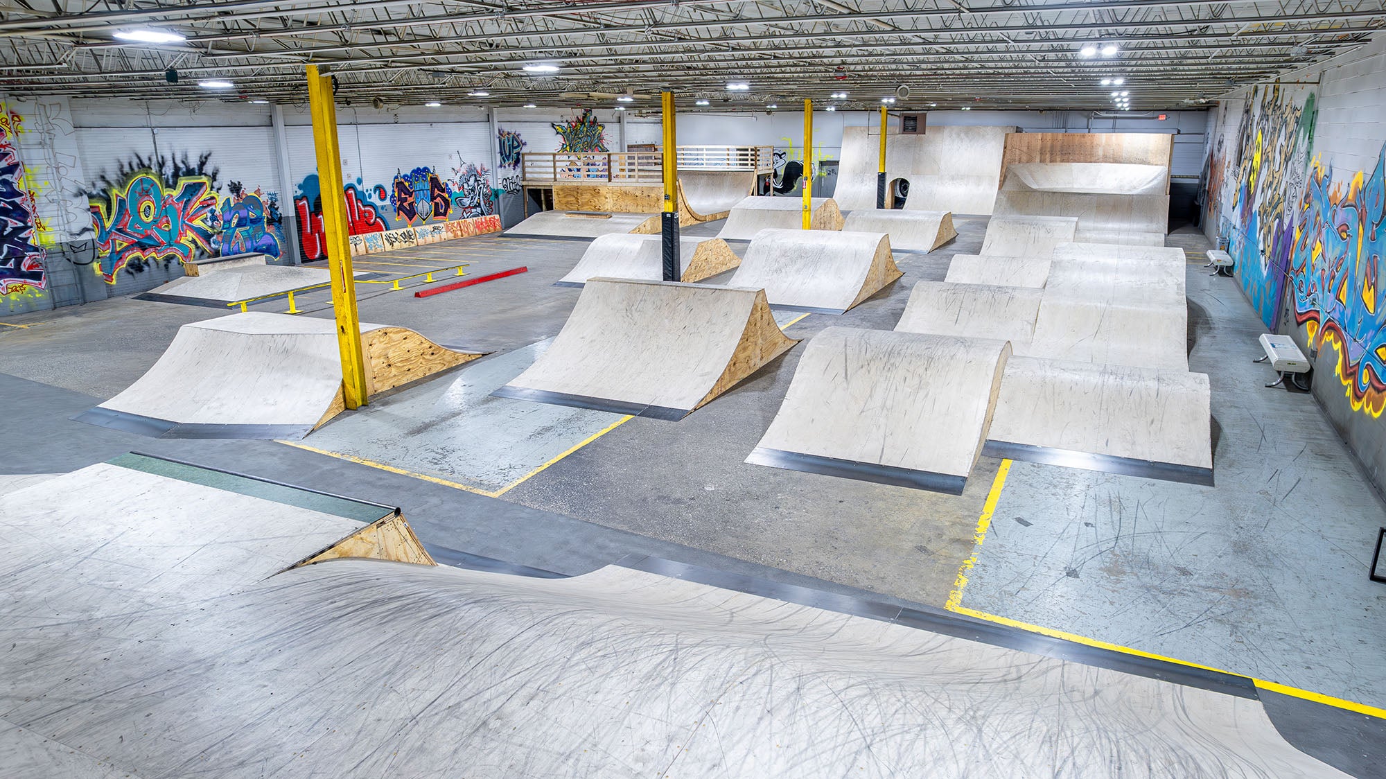 Indoor skate park with various ramps and graffiti on the walls.