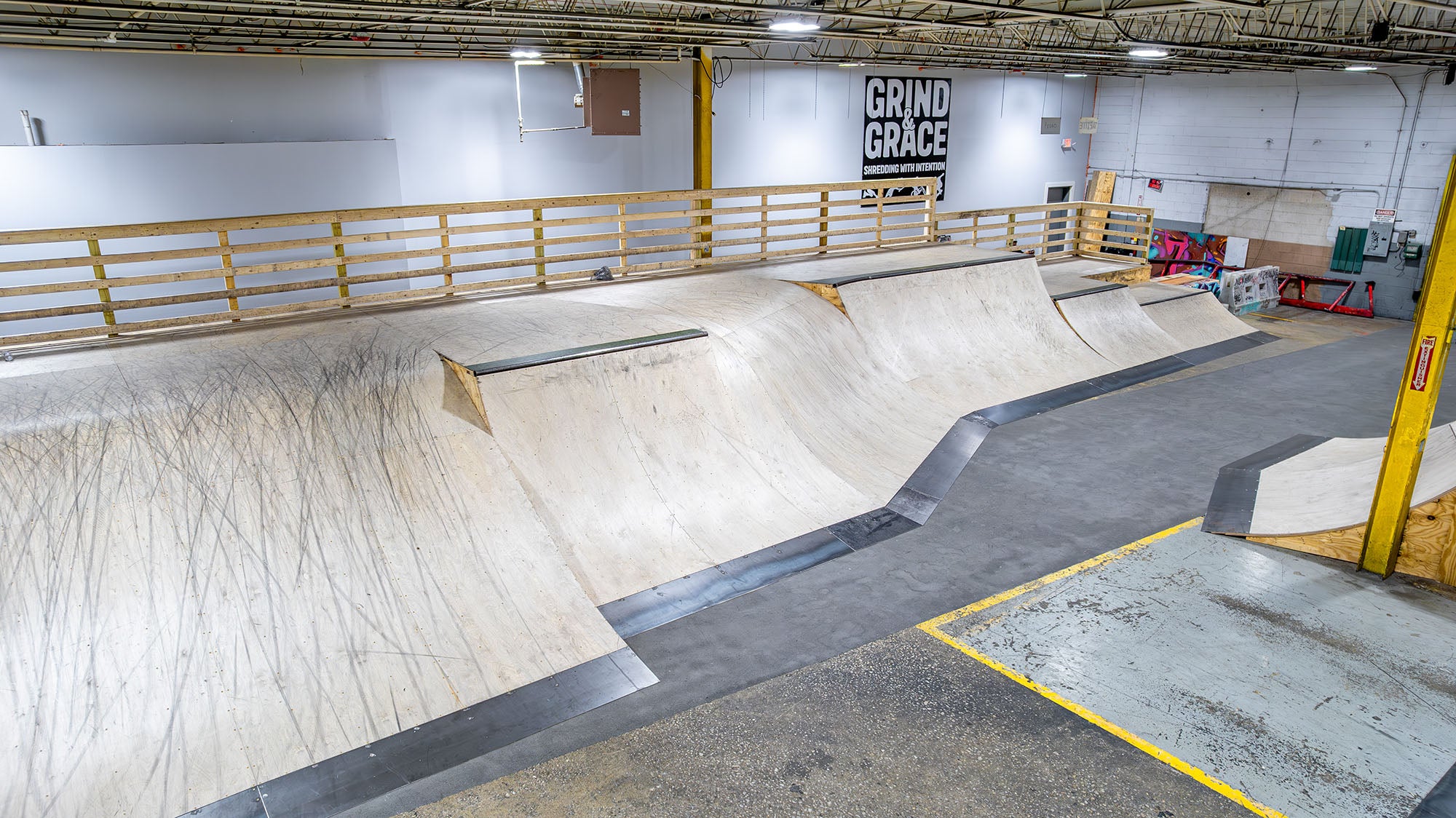 Indoor skate park with ramps and a 'Grind for Grace' banner on the wall.