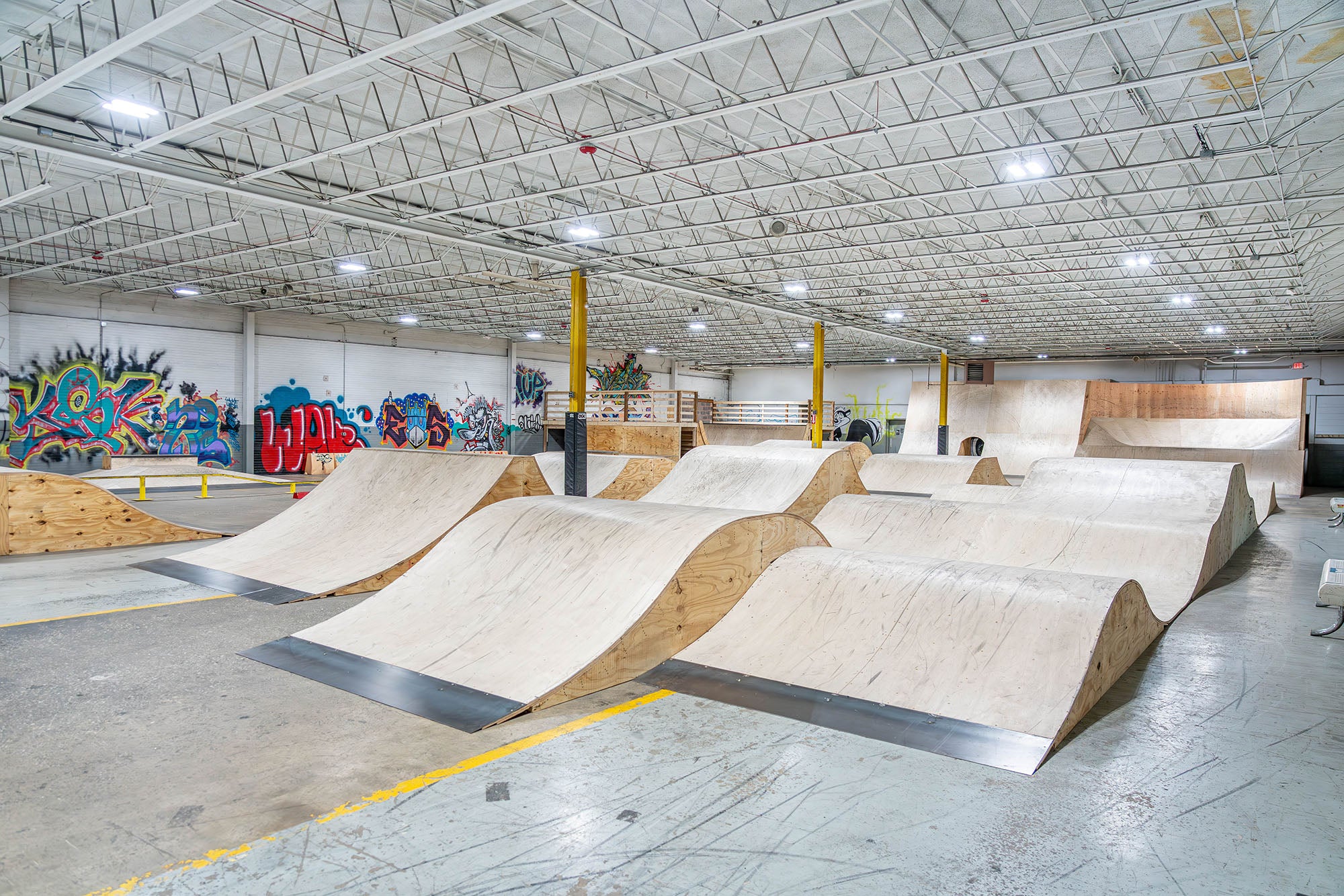 Indoor skate park with various ramps and graffiti art on the walls.