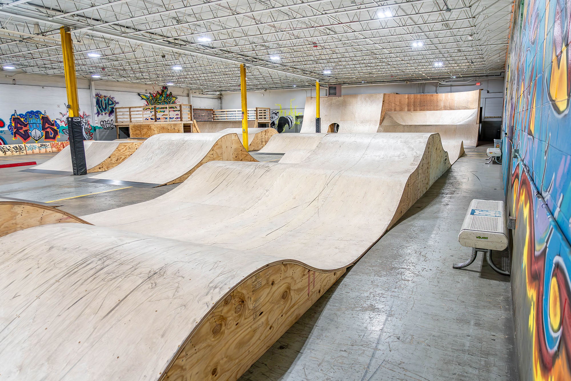 Indoor skate park with ramps and graffiti walls.