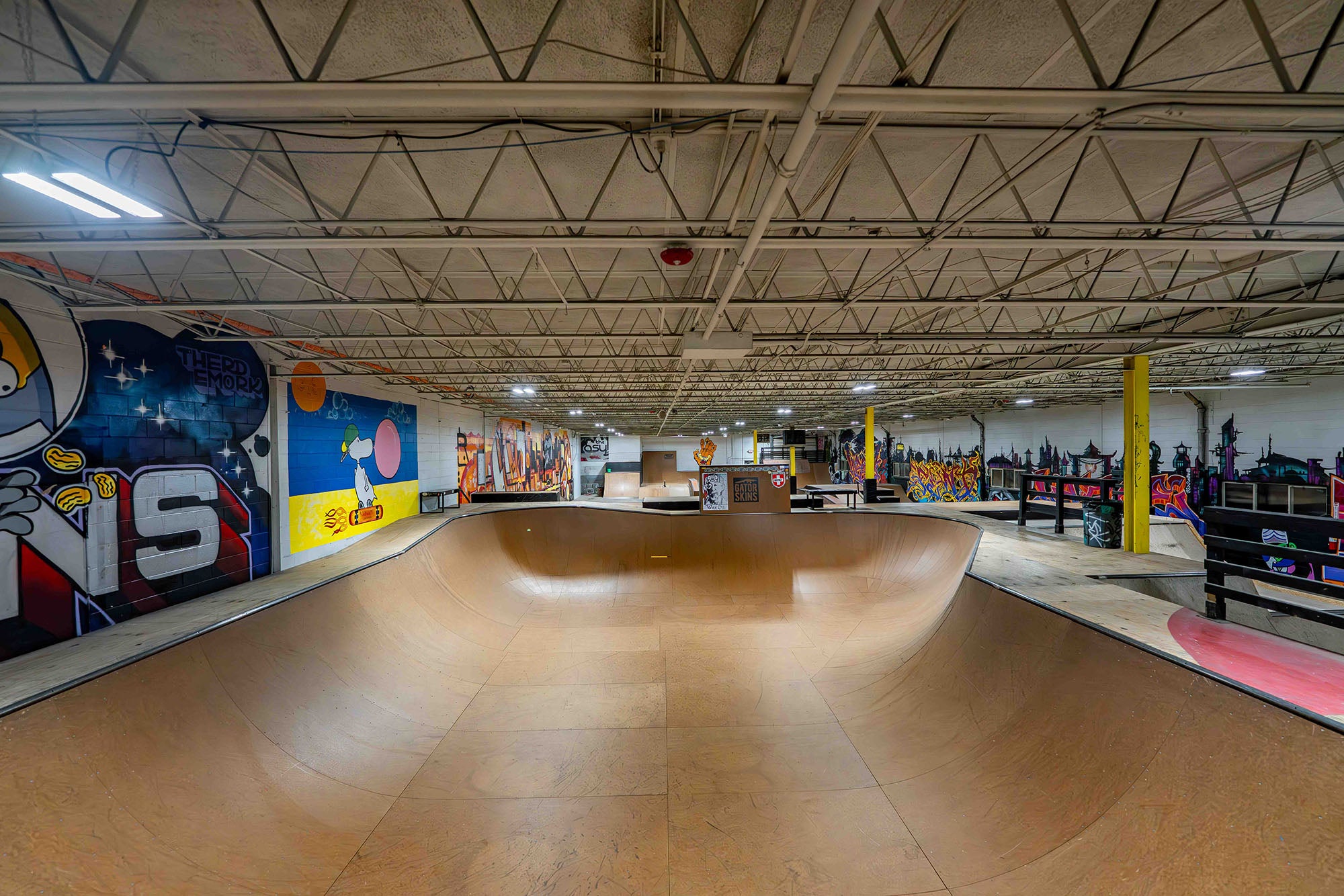 Indoor skate park with a large wooden bowl and colorful walls.