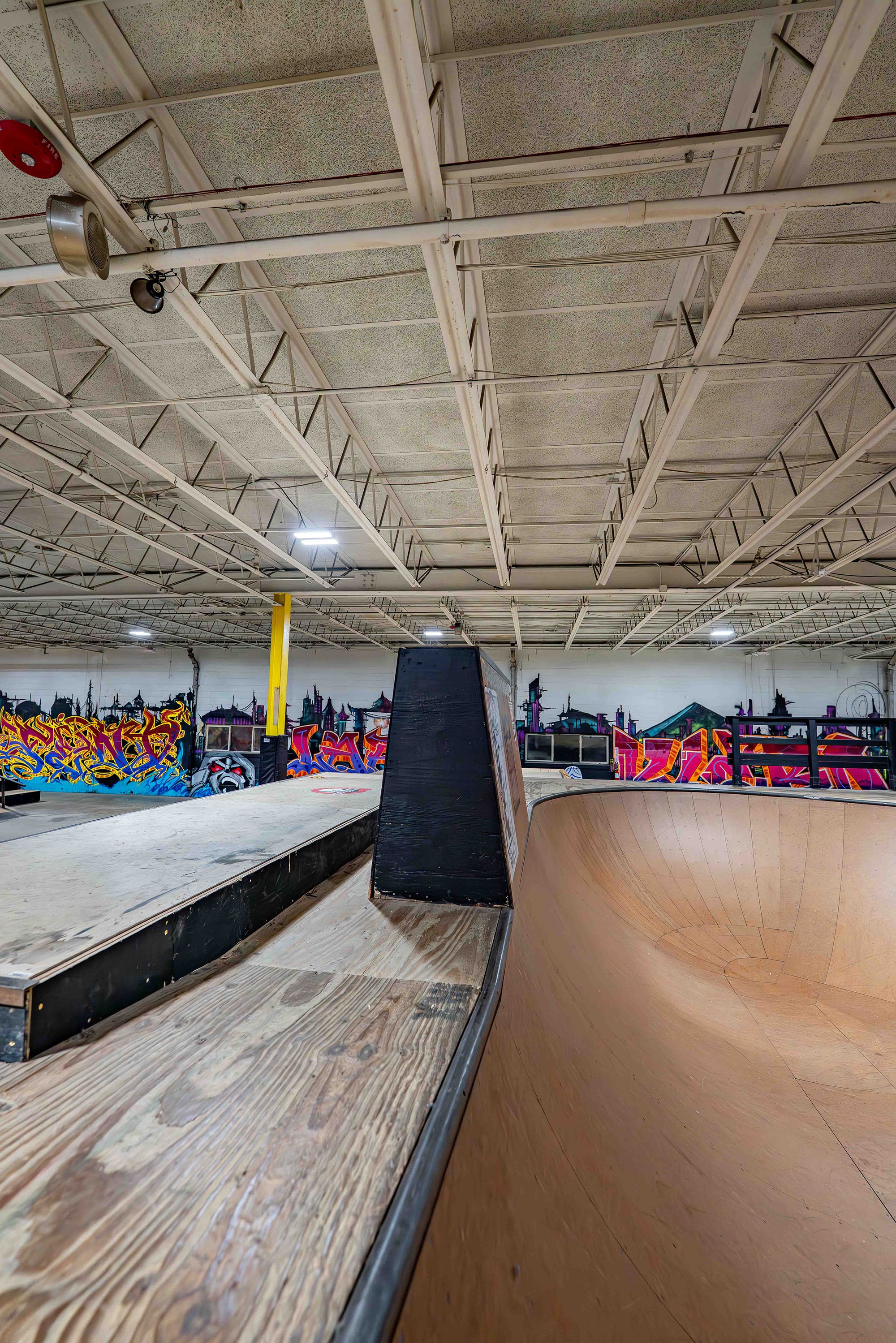 Indoor skate park with ramps and graffiti art on the walls.