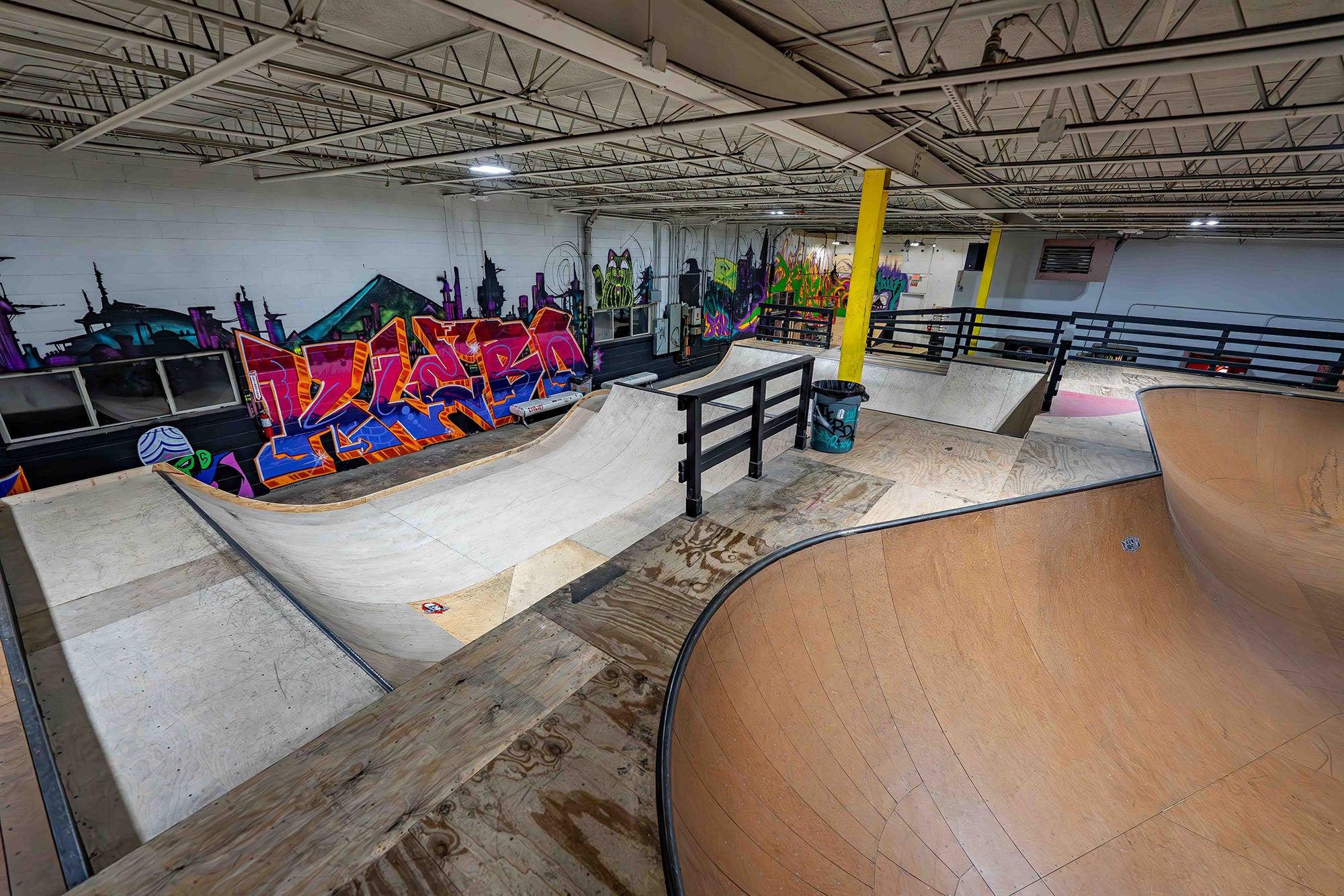 Indoor skate park with various ramps and graffiti art on the walls.