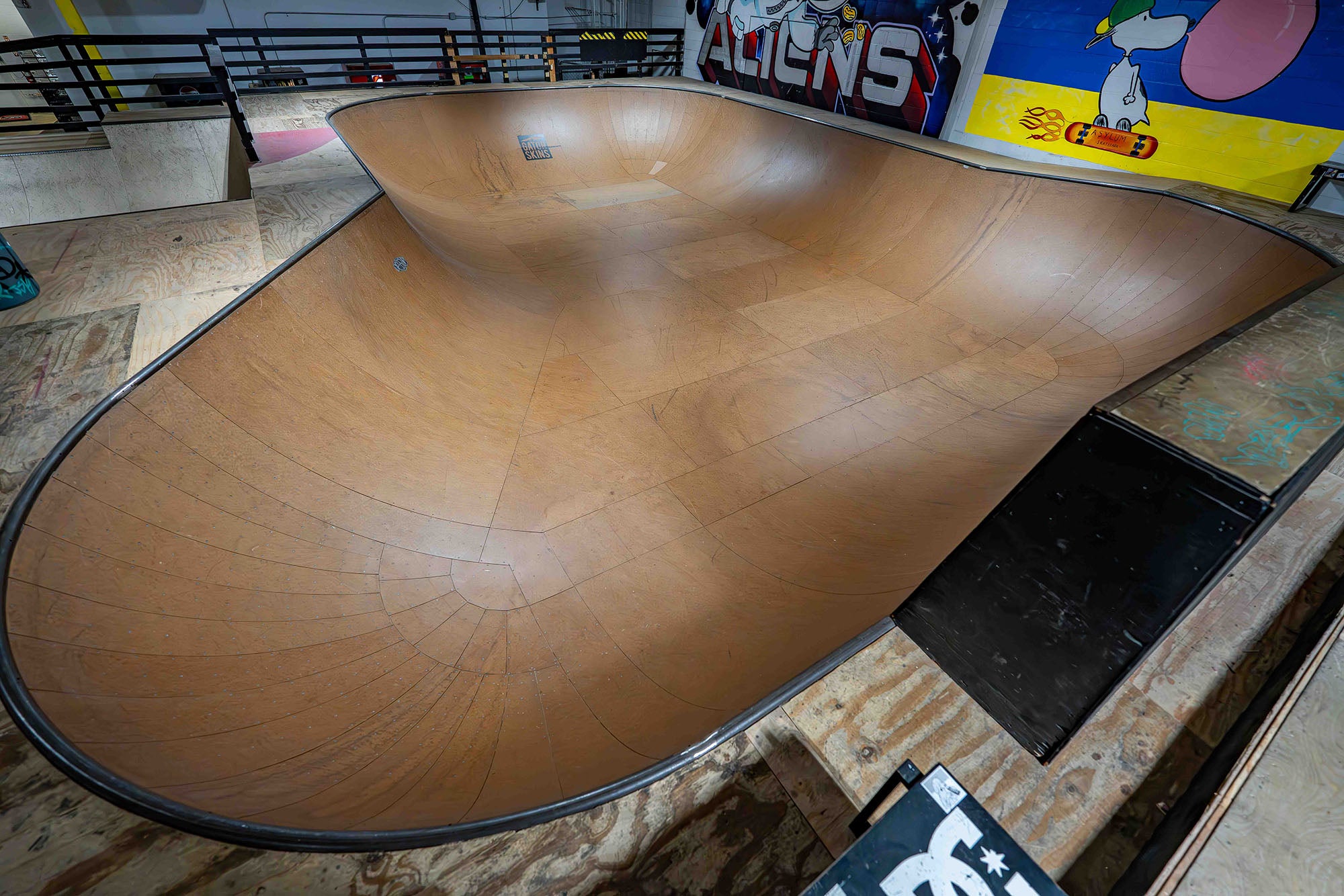 Wooden skateboard ramp with a worn surface in an indoor setting