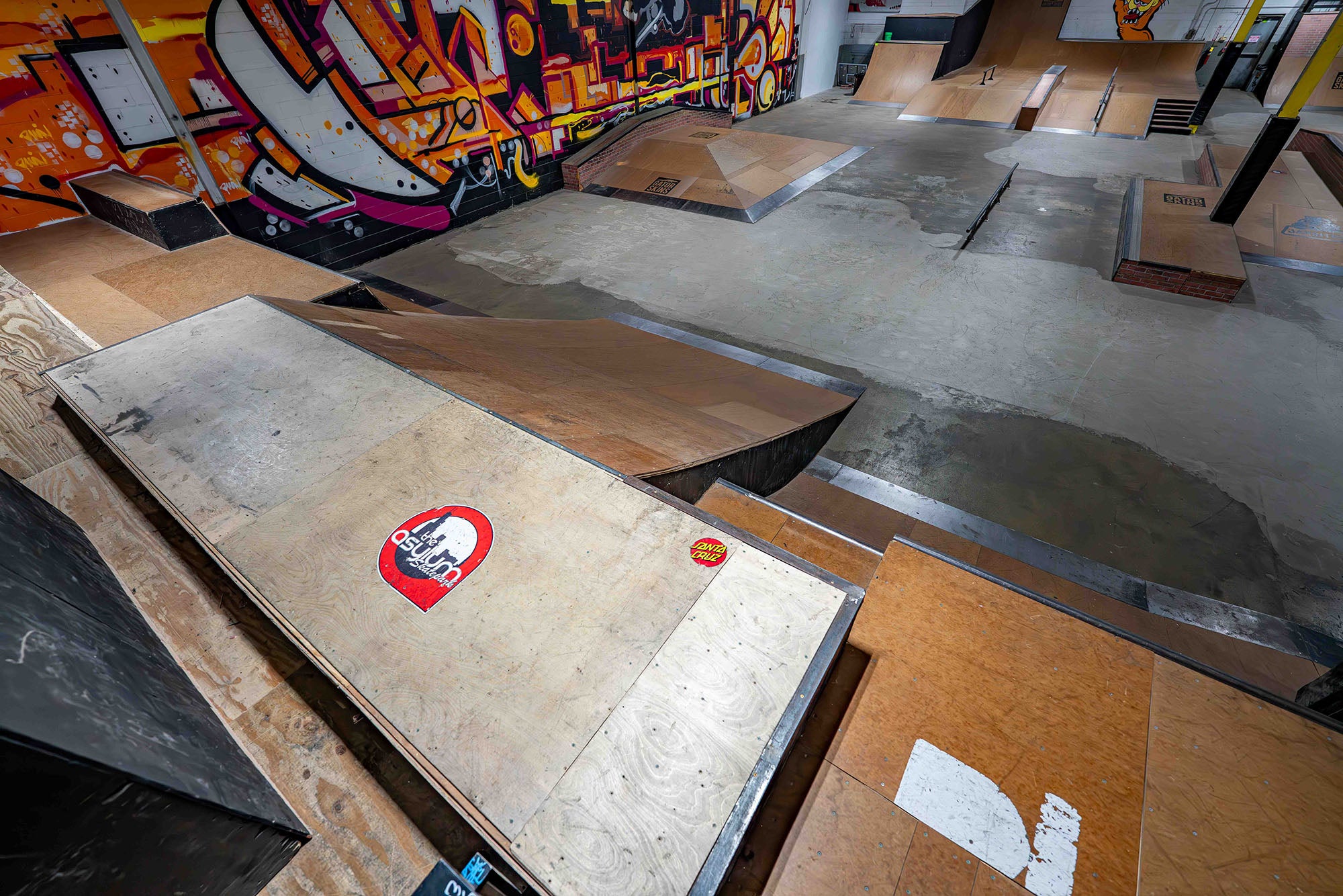 Skateboard ramps with stickers in a graffiti-covered indoor setting