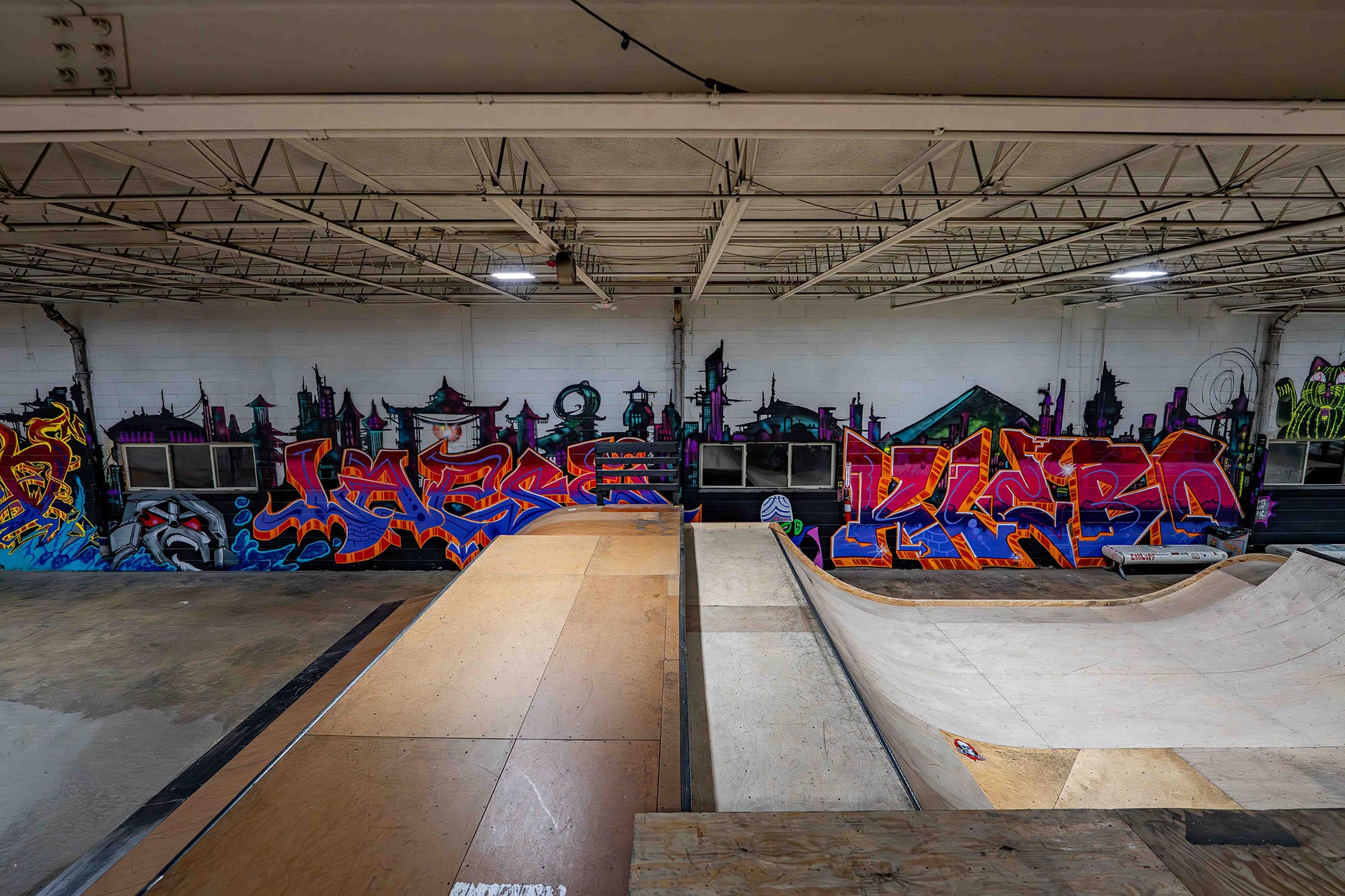 Indoor skate park with colorful graffiti art on walls and ramps.