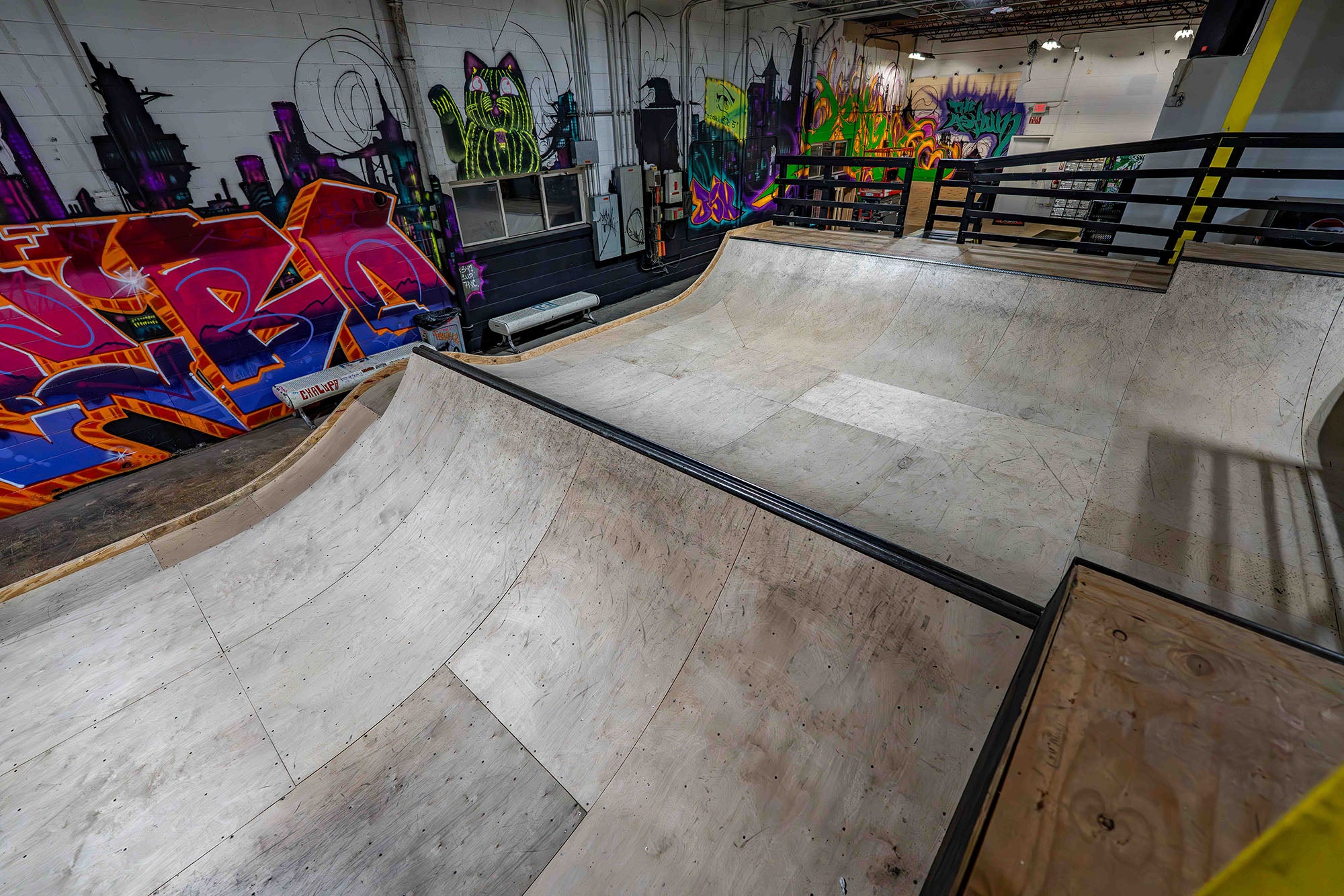 Indoor skate park with ramps and colorful graffiti on the walls.