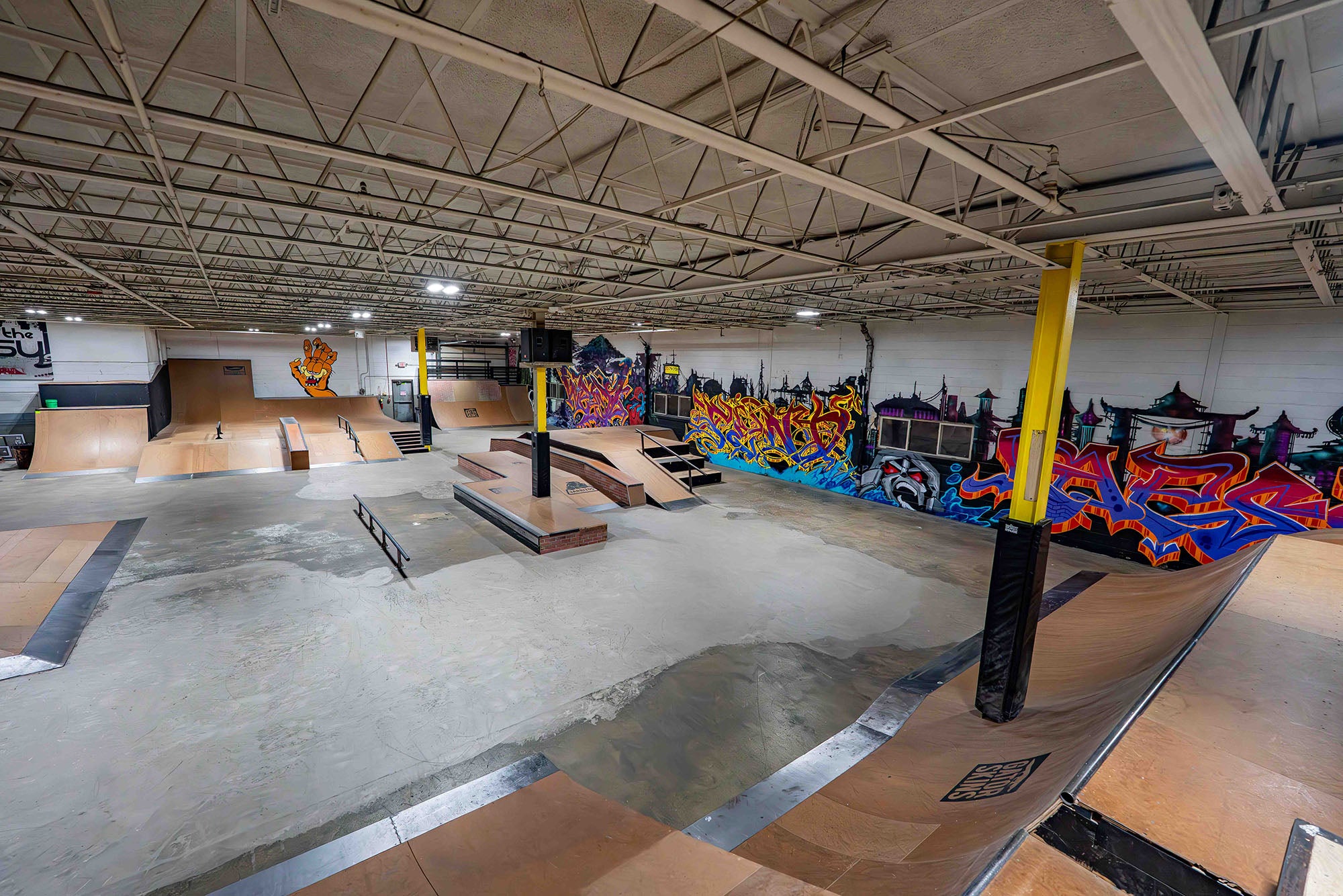 Indoor skate park with various ramps and graffiti art on the walls.