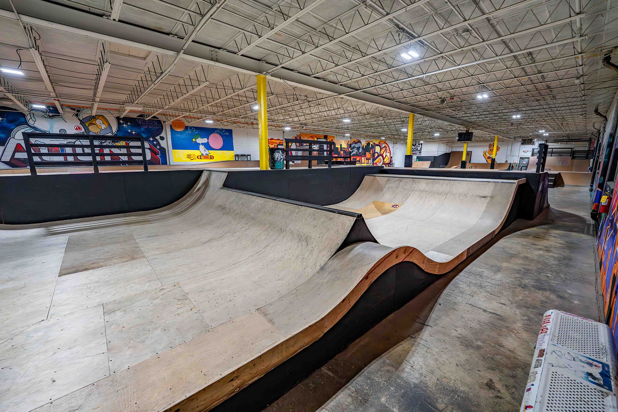 Indoor skate park with ramps and various decorations on the walls.