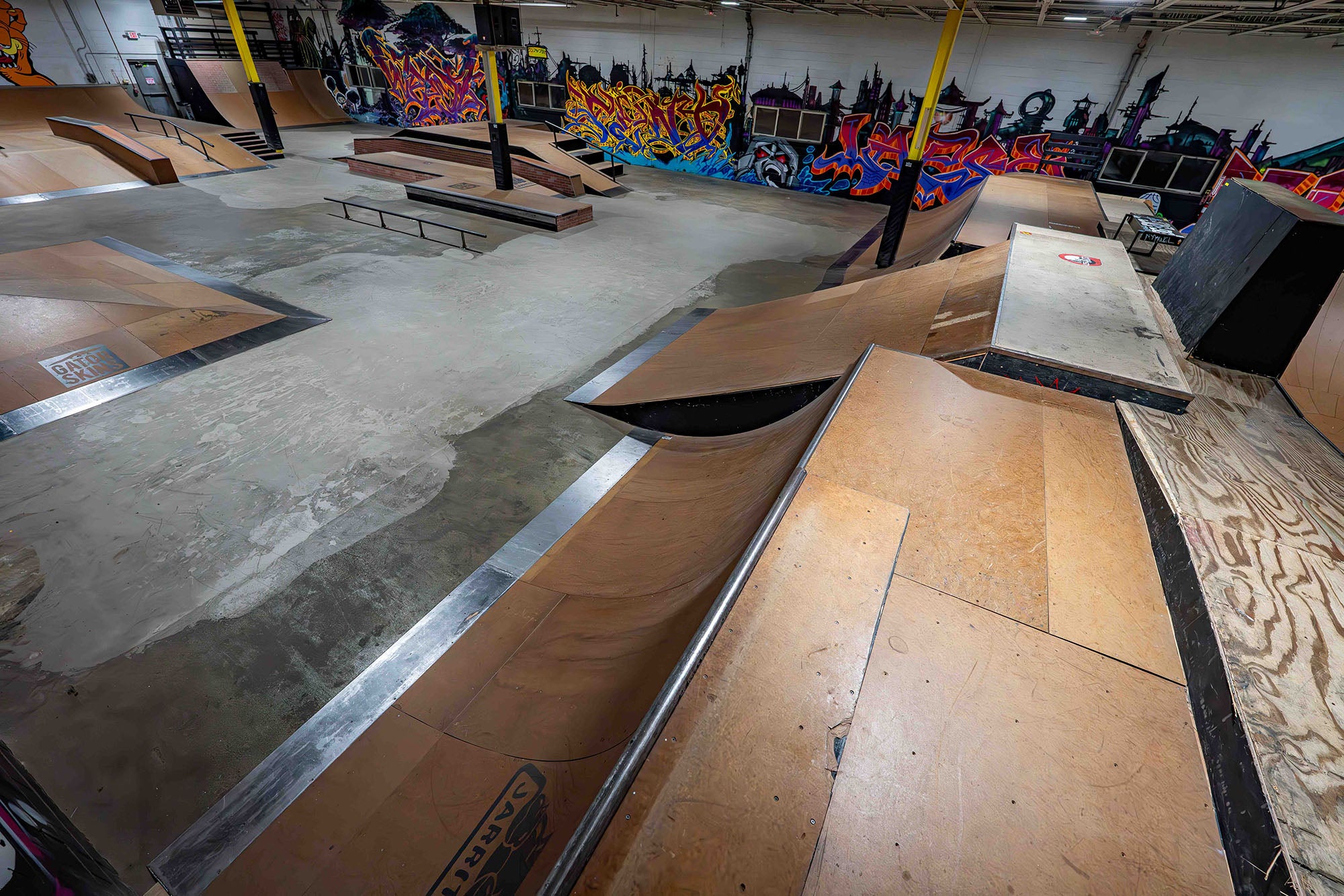Indoor skate park with various ramps and graffiti on the walls