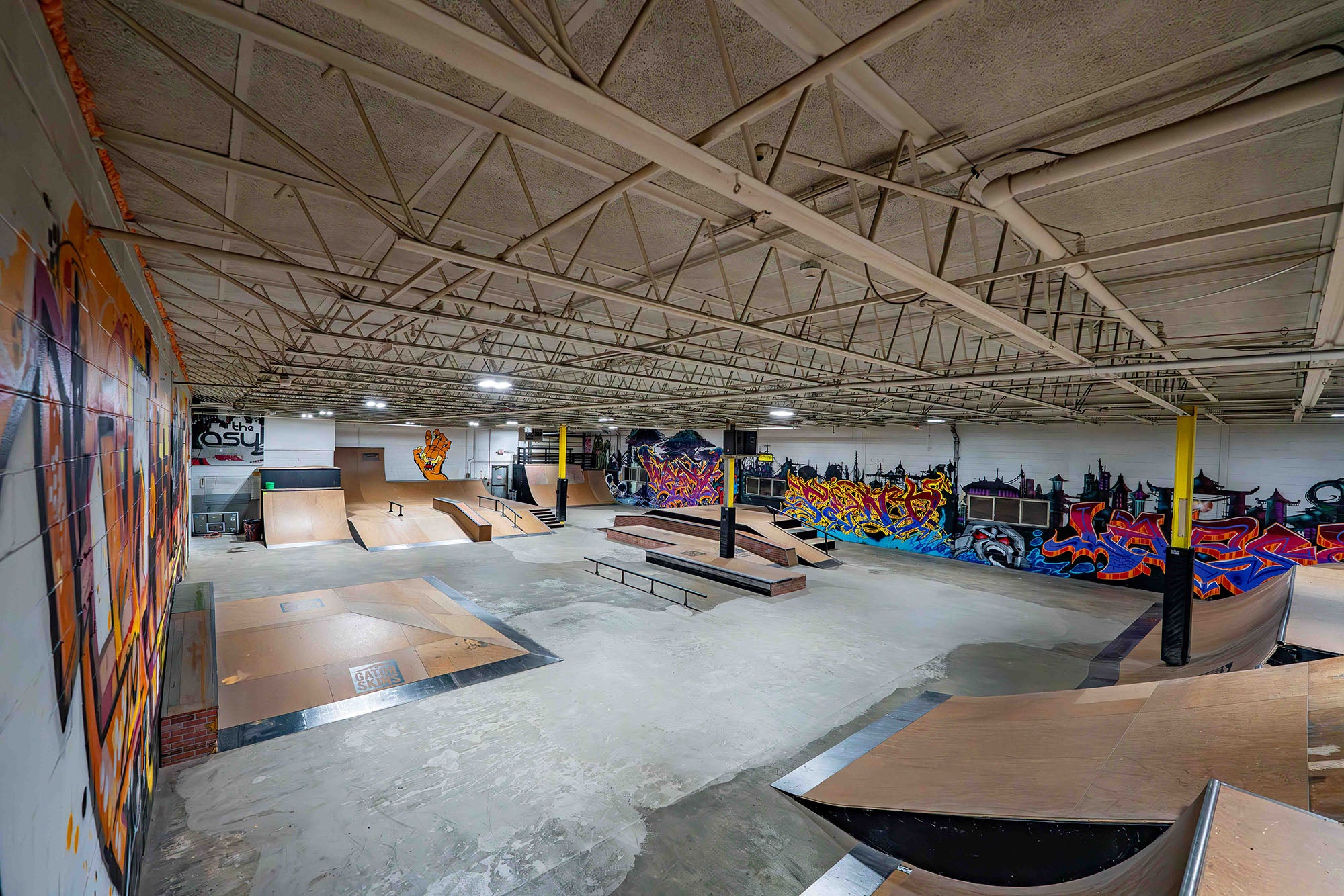 Indoor skate park with various ramps and graffiti art on the walls.