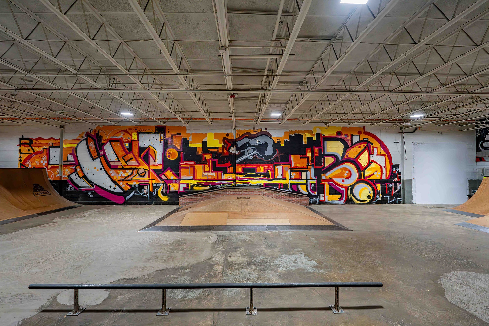Skate park interior with colorful graffiti art on the wall.