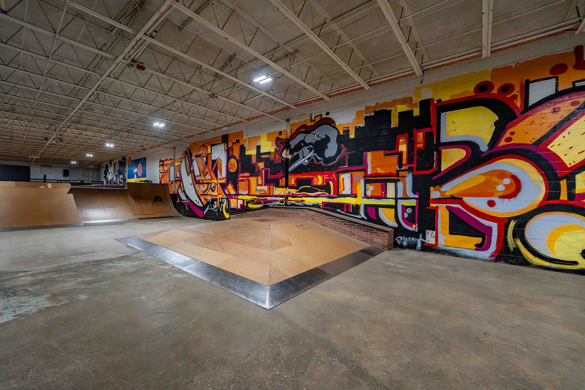 Indoor skate park with colorful graffiti art on the walls.