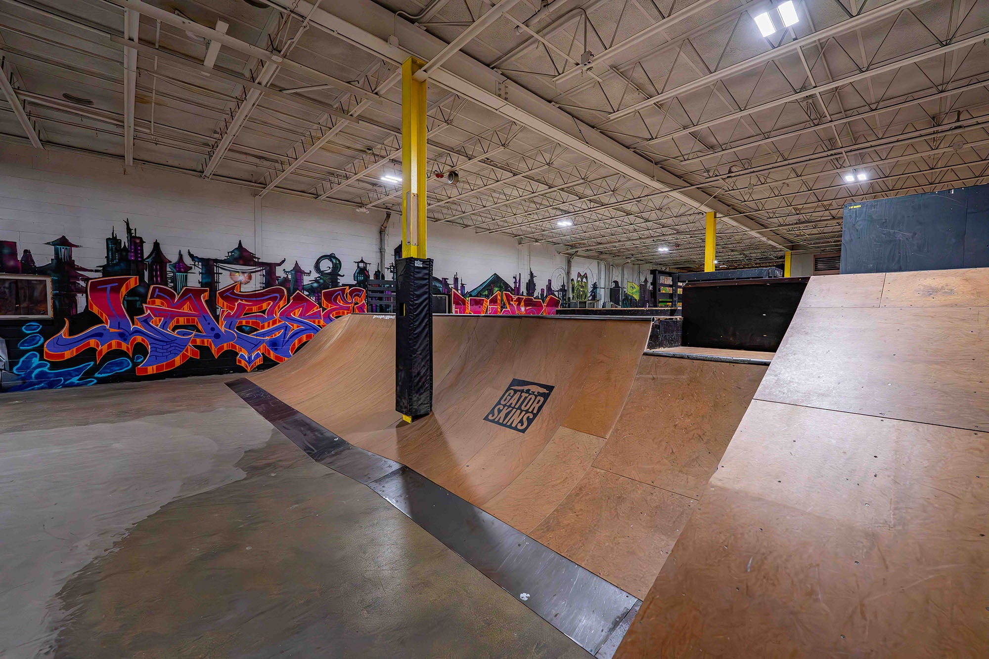 Indoor skate park with ramps and graffiti art on the walls.