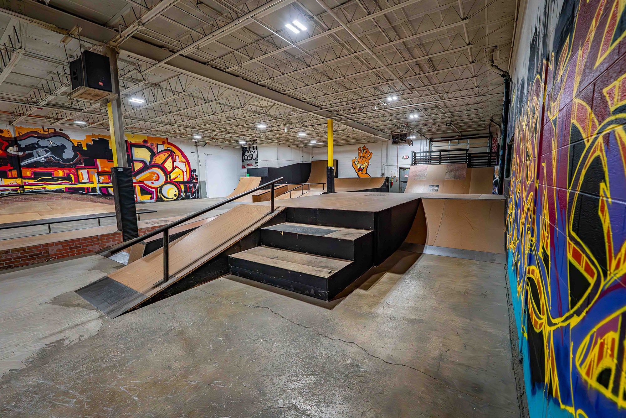 Indoor skate park with ramps and graffiti art on the walls.