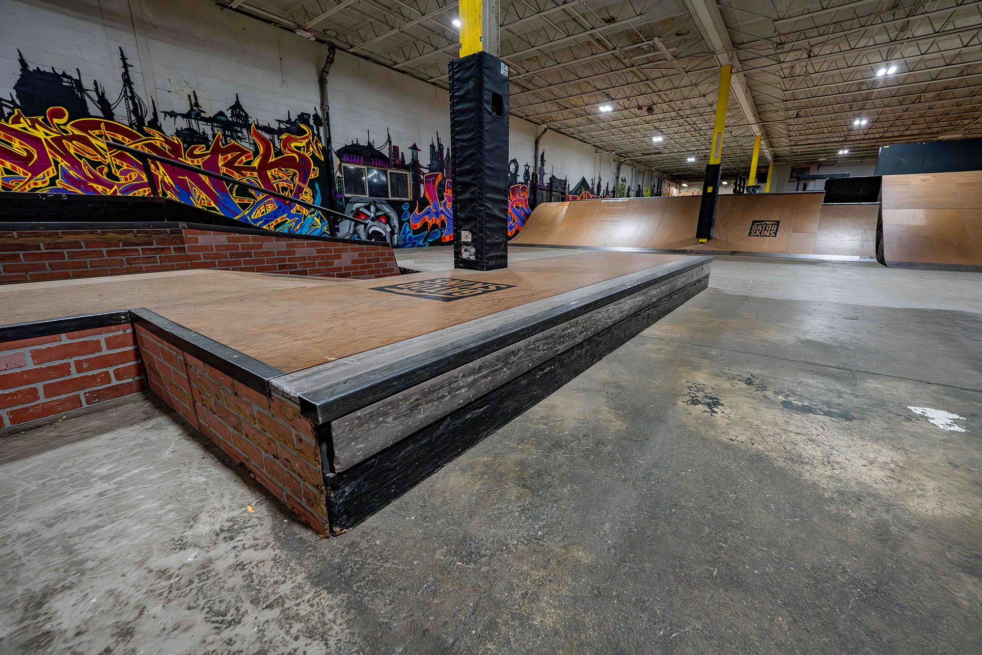 Indoor skate park with ramps and graffiti art on the walls.