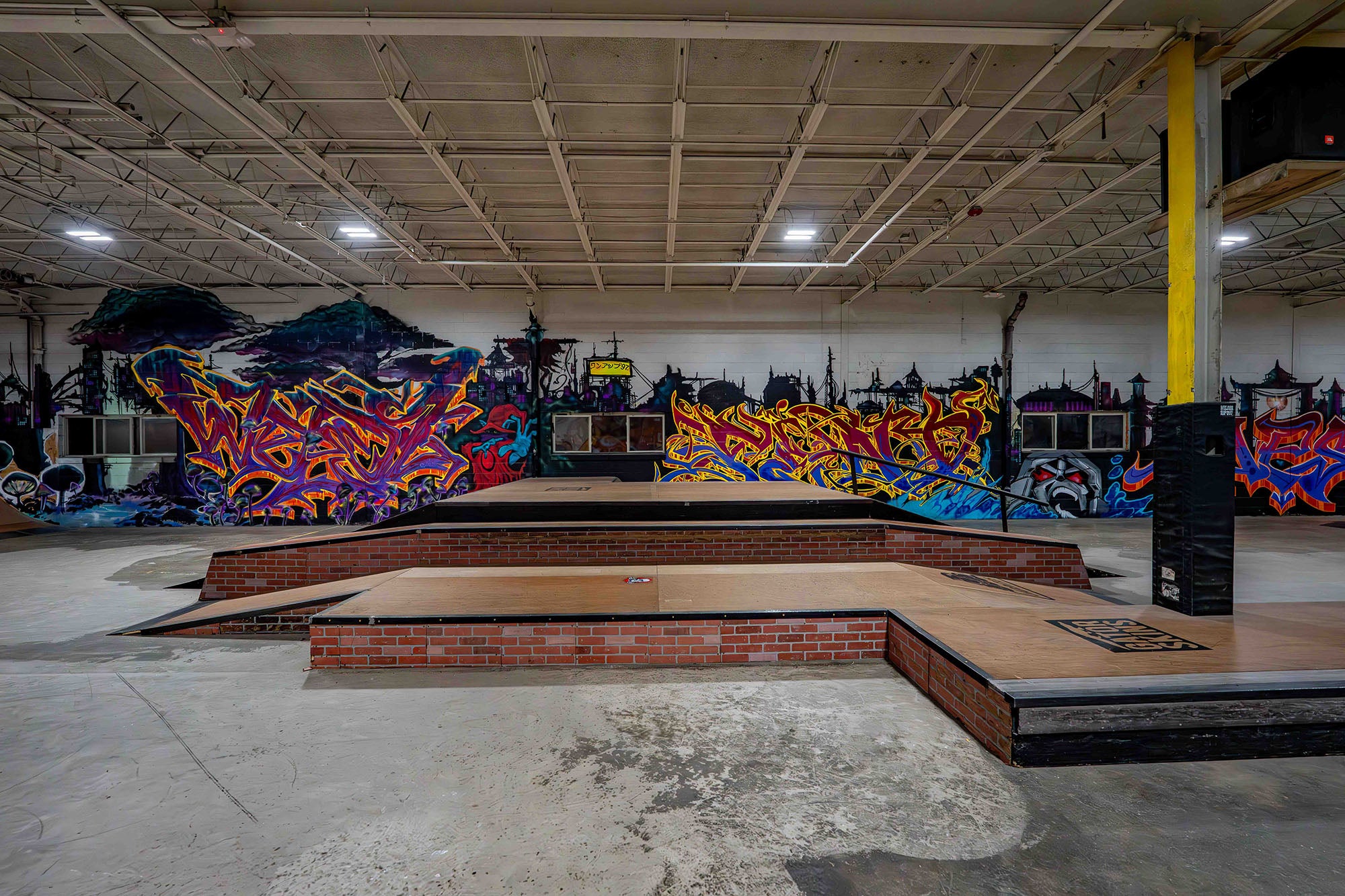 Indoor skate park with ramps and colorful graffiti art on the walls.