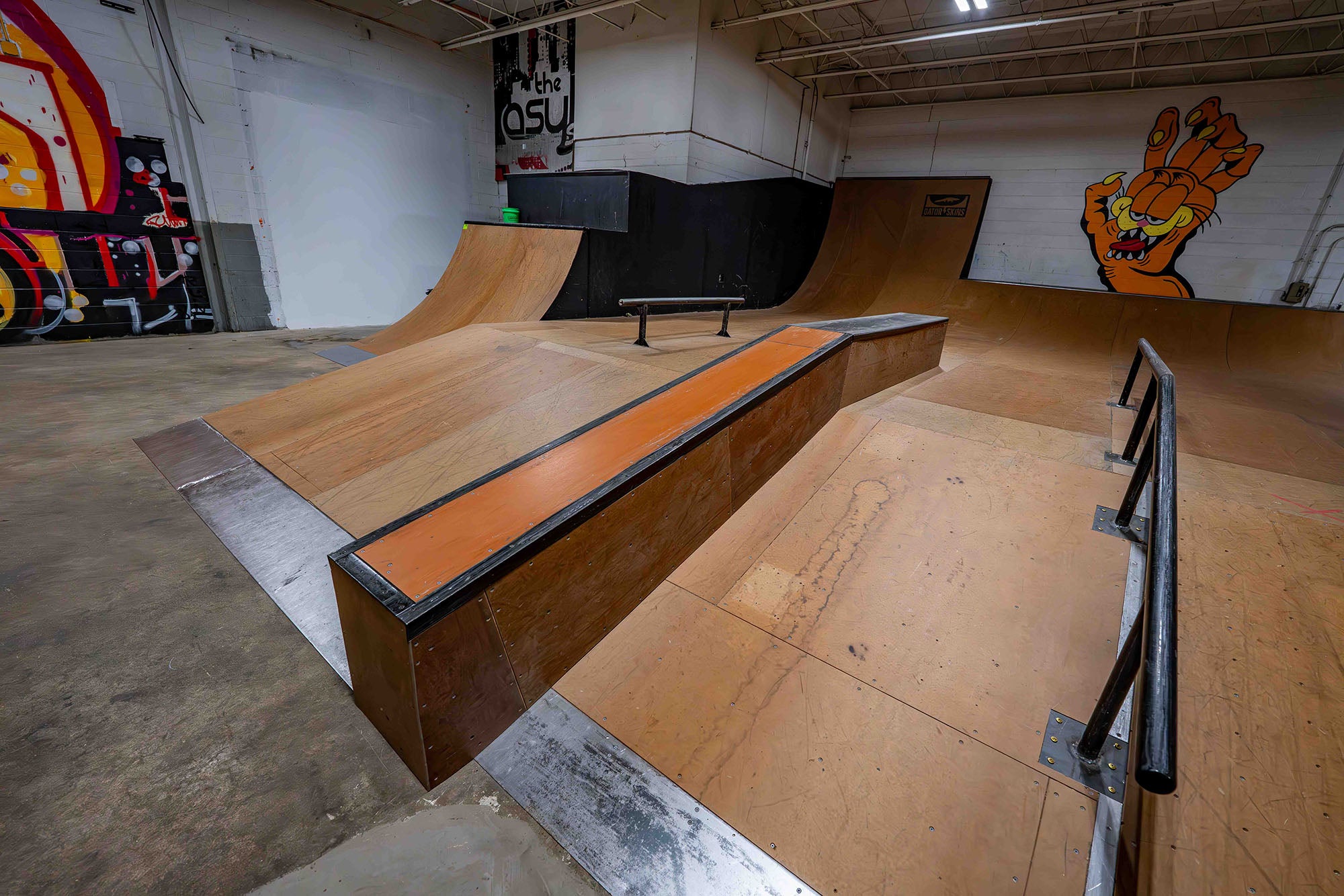 Skate park with wooden ramps and railings on a concrete floor.