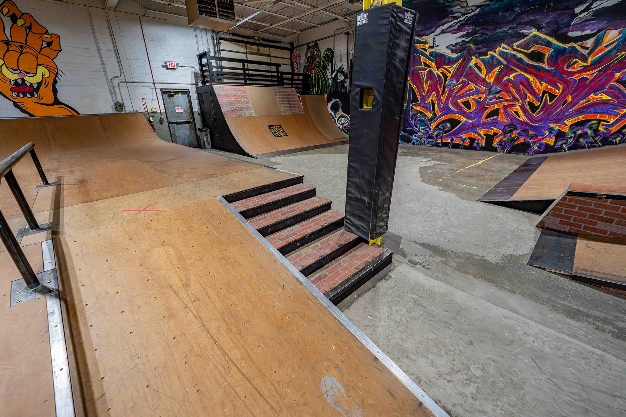 Indoor skate park with wooden ramps and colorful wall art