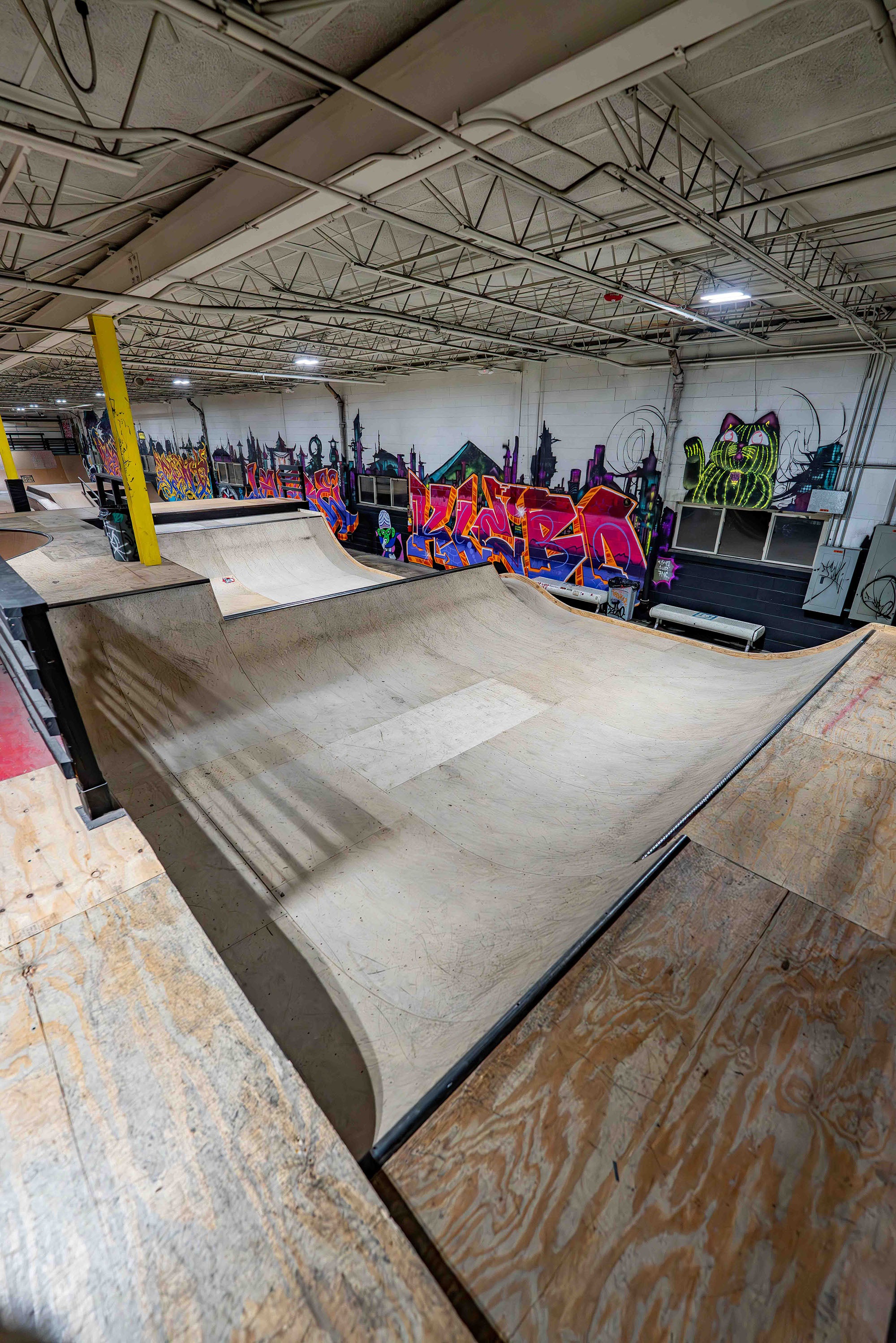 Indoor skate park with ramps and graffiti art on the walls.