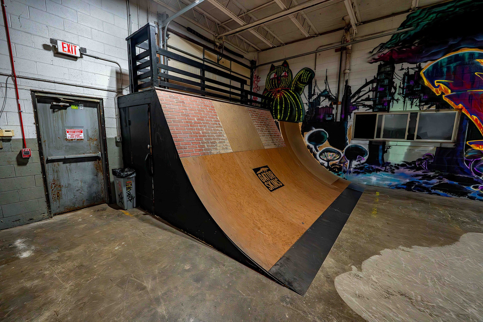 Wooden skateboard ramp inside a warehouse with graffiti on the walls.