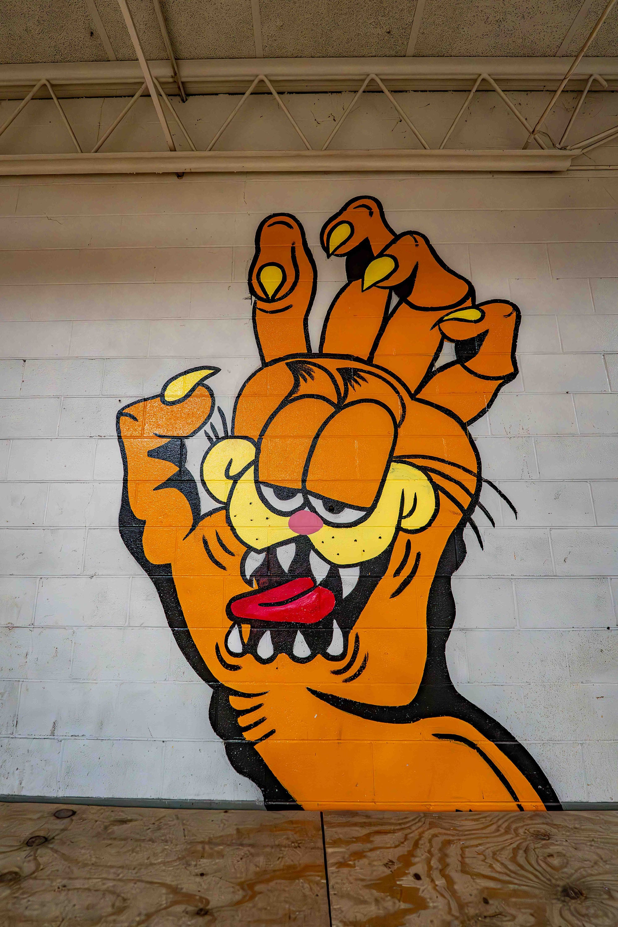Cartoon tiger character with a hand on a white wall.
