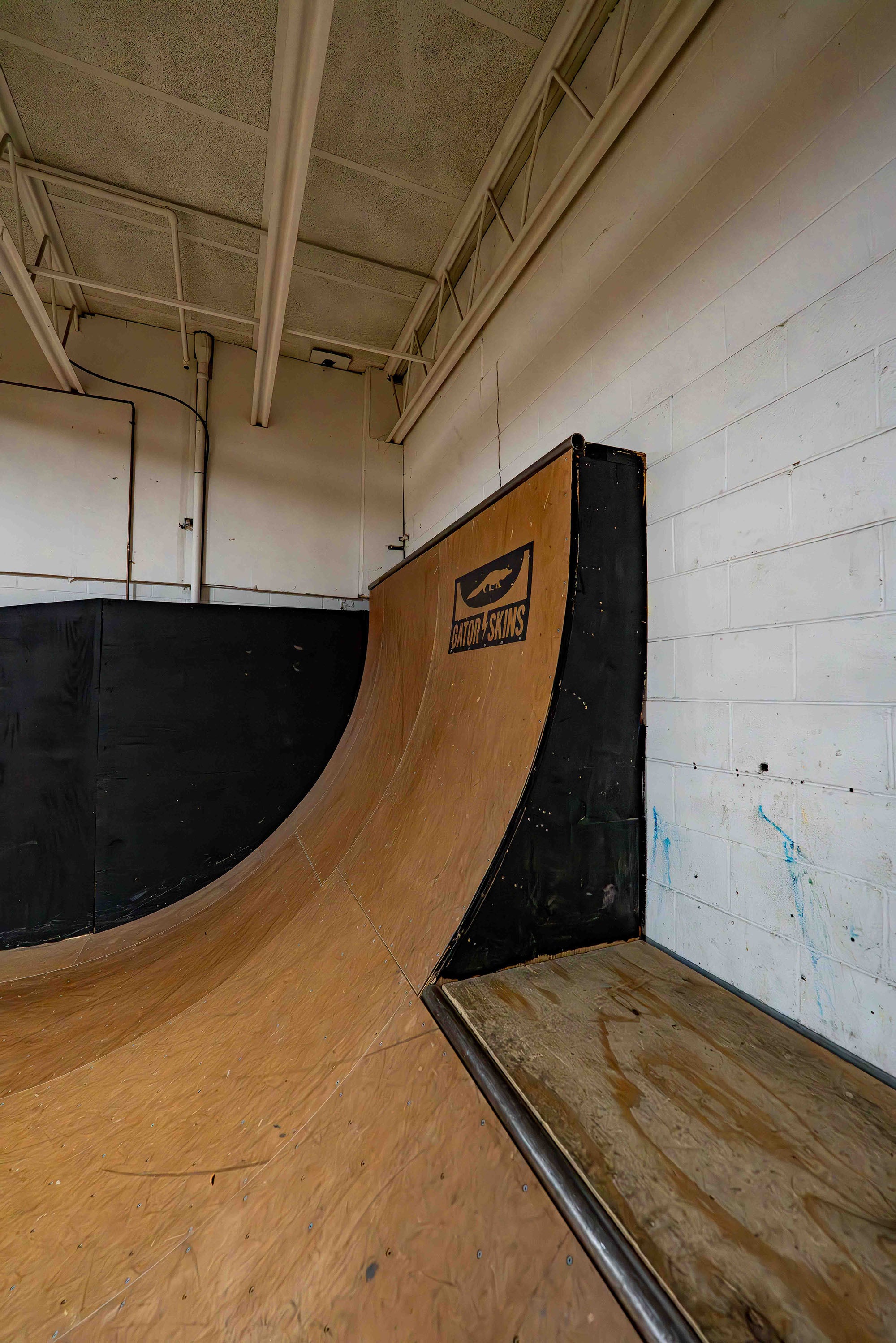 Wooden skateboard ramp inside a building with a visible brand logo on the side.