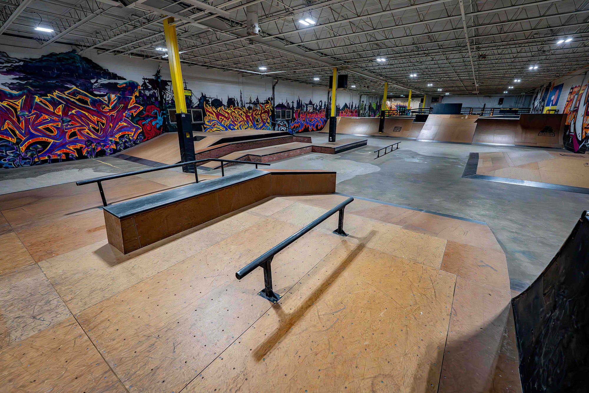 Indoor skate park with various ramps and graffiti art on the walls.