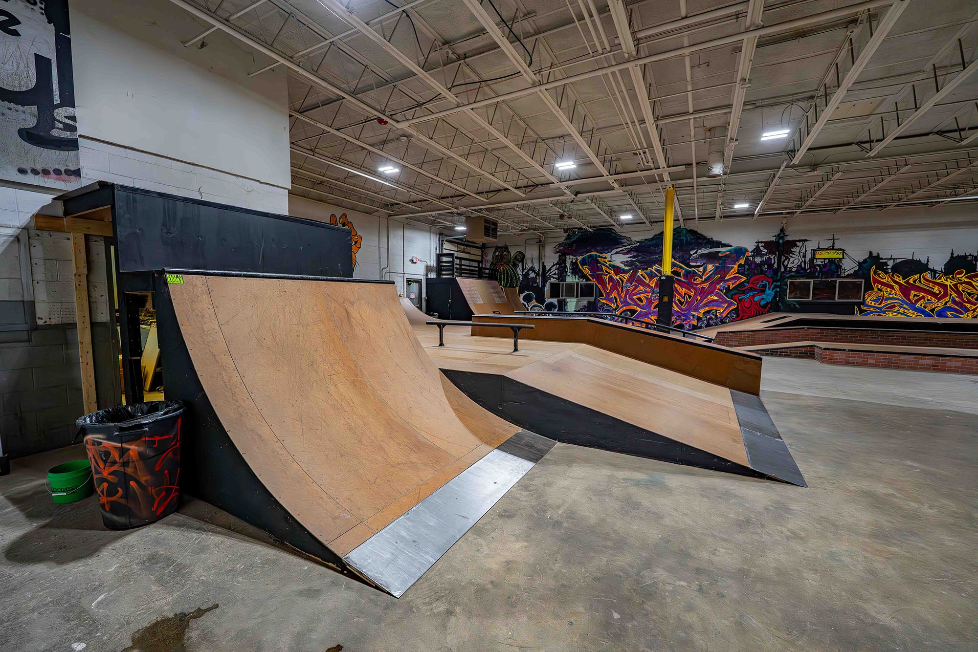Indoor skate park with ramps and colorful decorations on the walls.