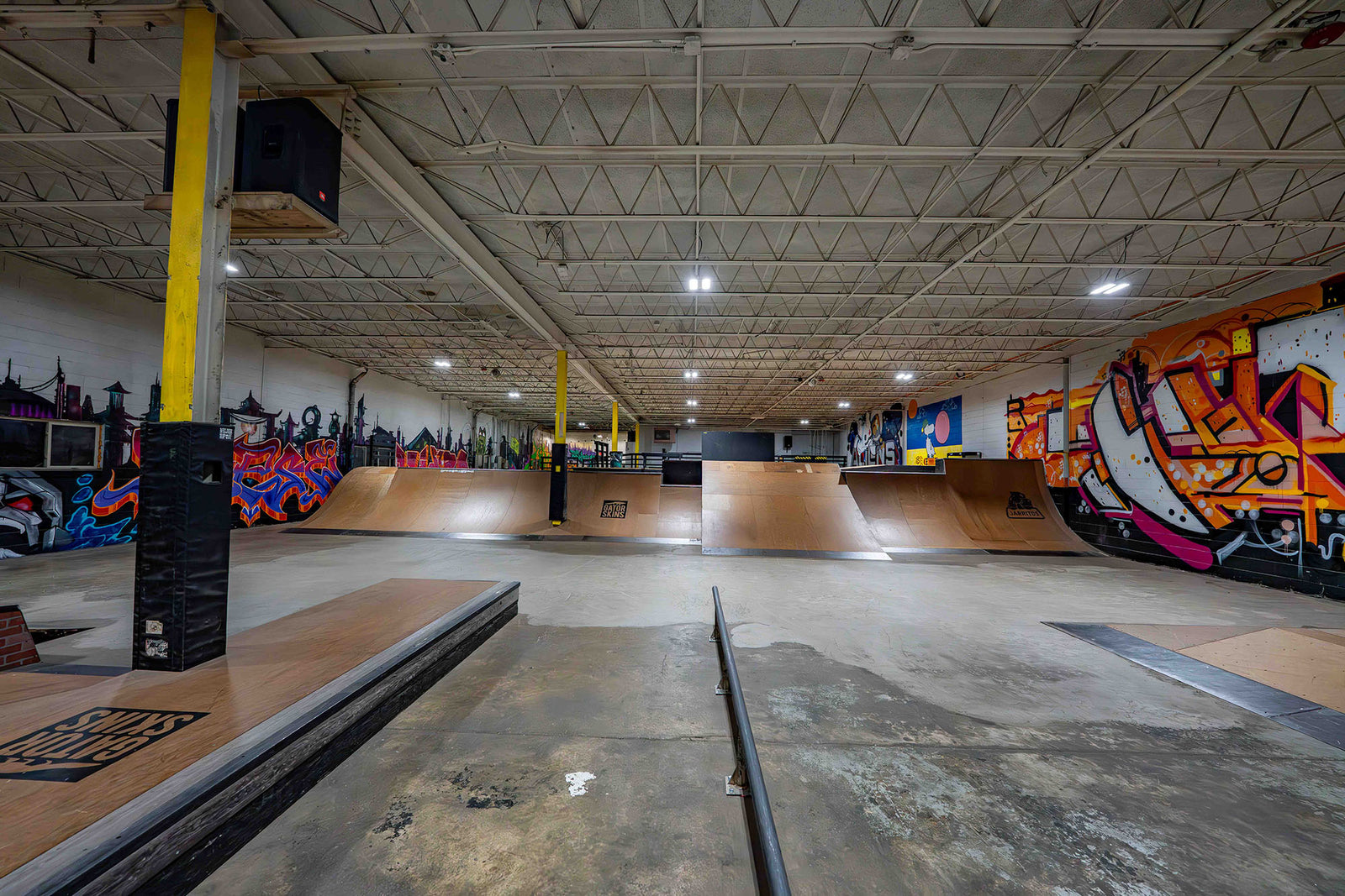 Indoor skate park with ramps and graffiti art on the walls.