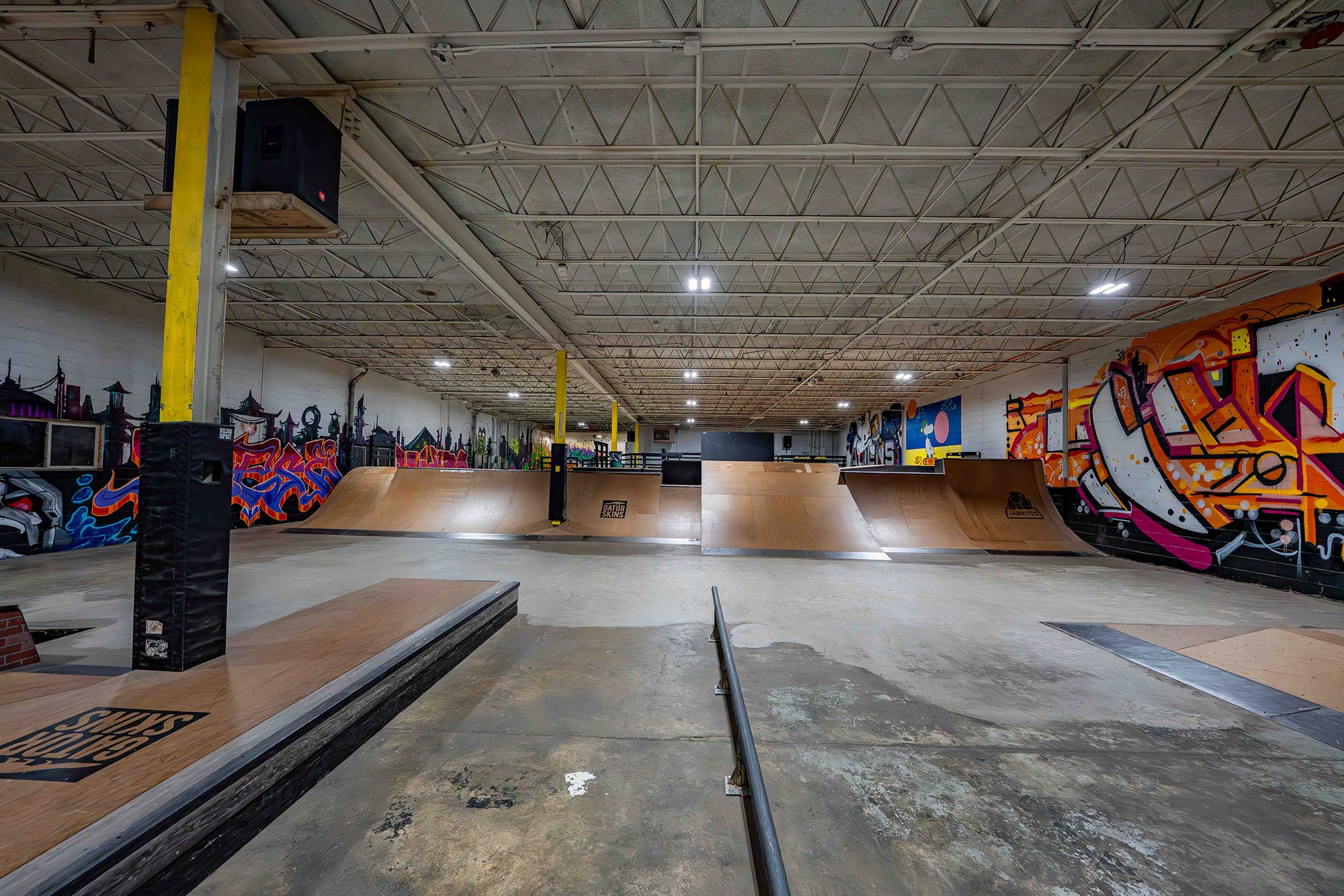 Indoor skate park with ramps and graffiti art on the walls.