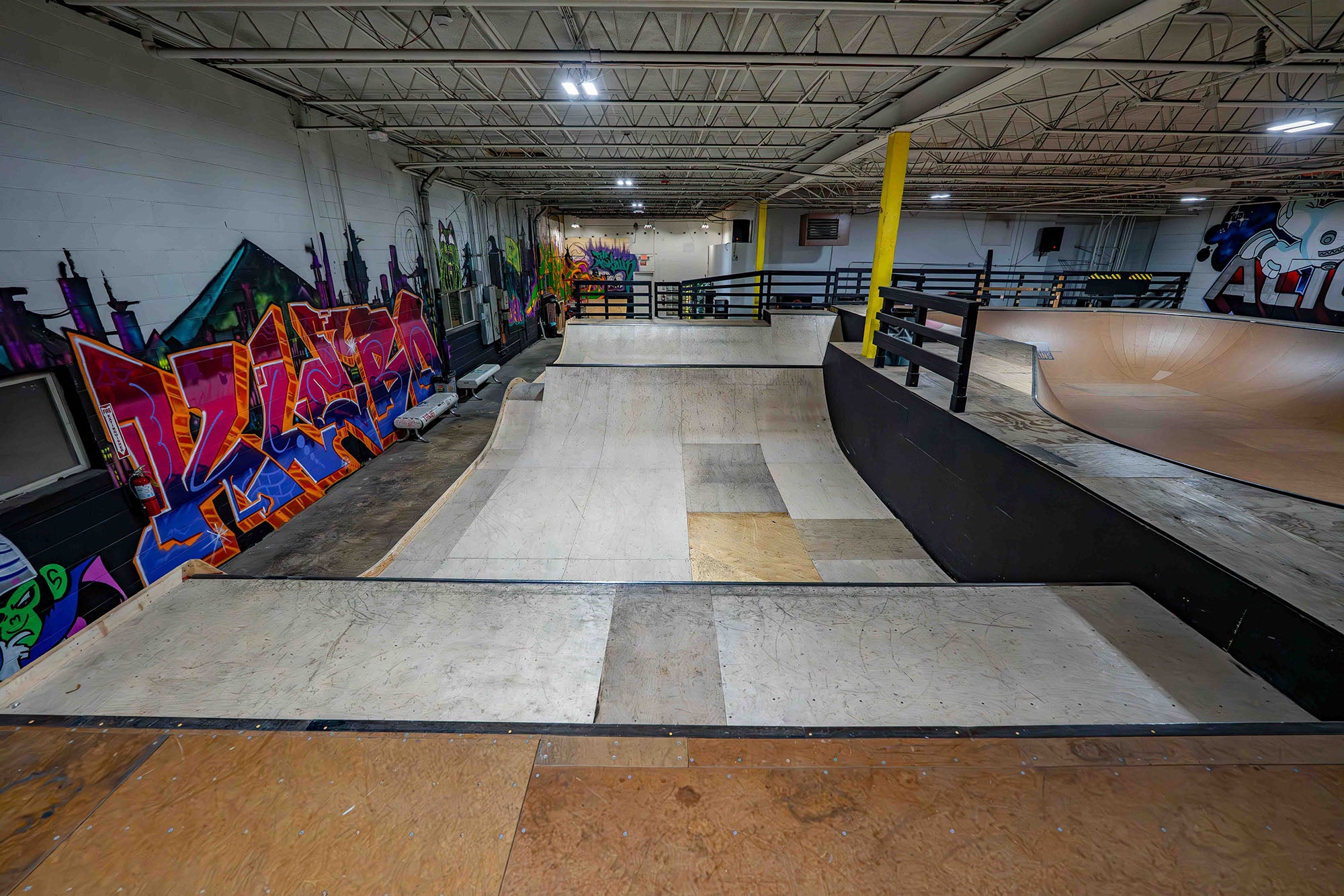 Indoor skate park with ramps and graffiti art on the walls.