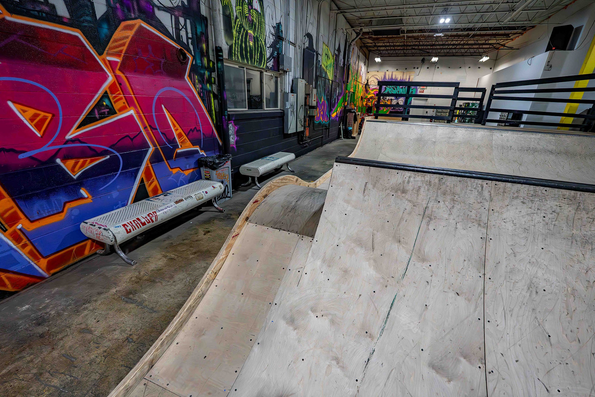 Indoor skate park with ramps and colorful graffiti on the walls.