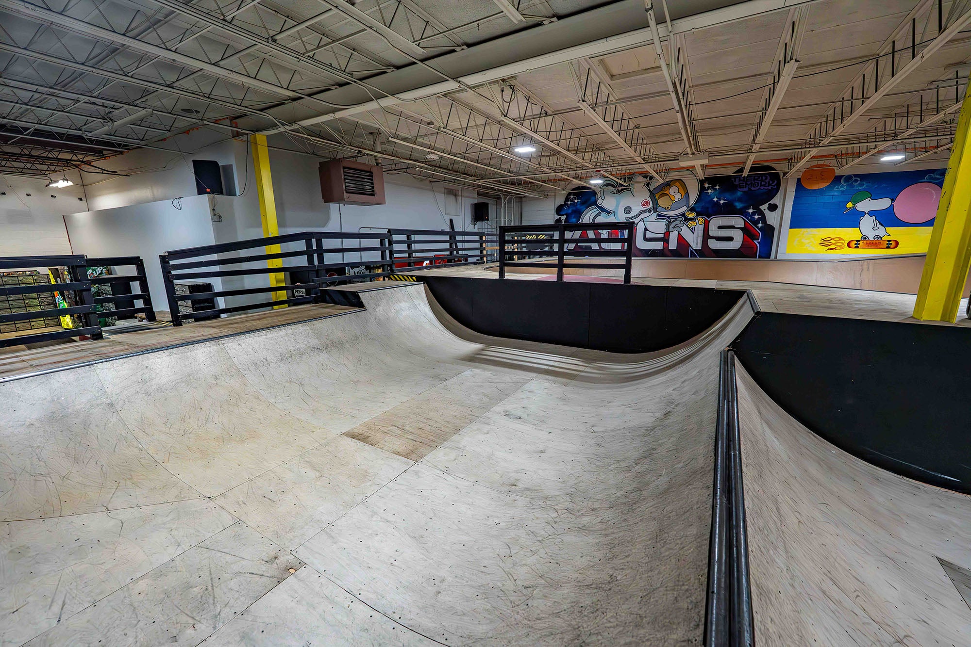 Indoor skate park with ramps and graffiti art on the wall.