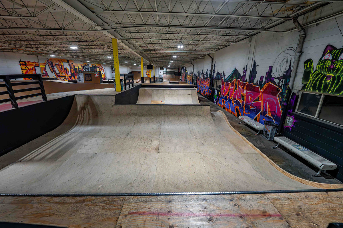 Indoor skate park with ramps and graffiti art on the walls.