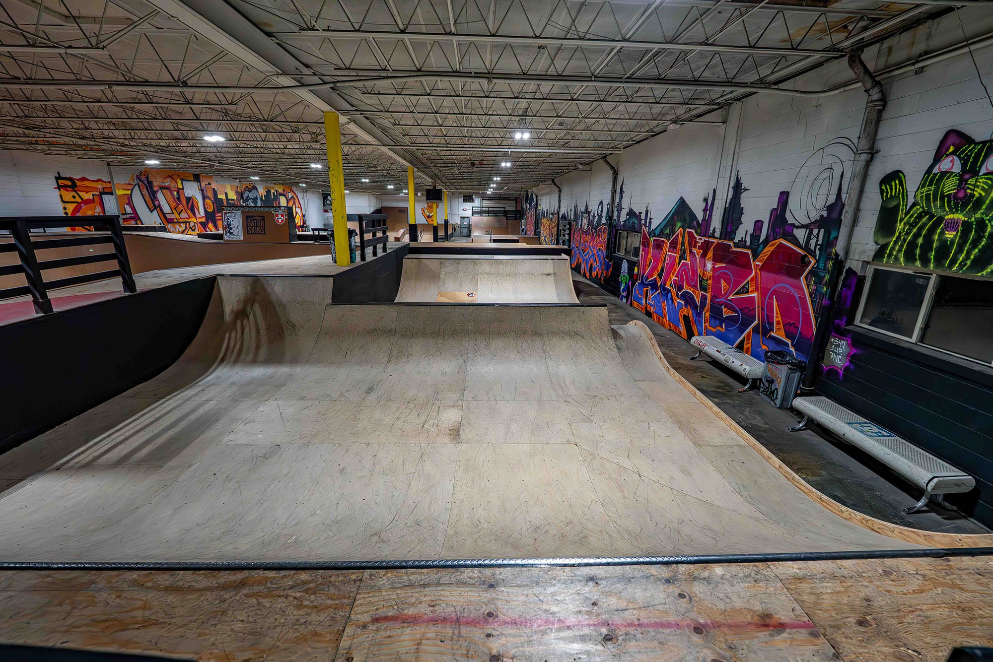 Indoor skate park with ramps and graffiti art on the walls.